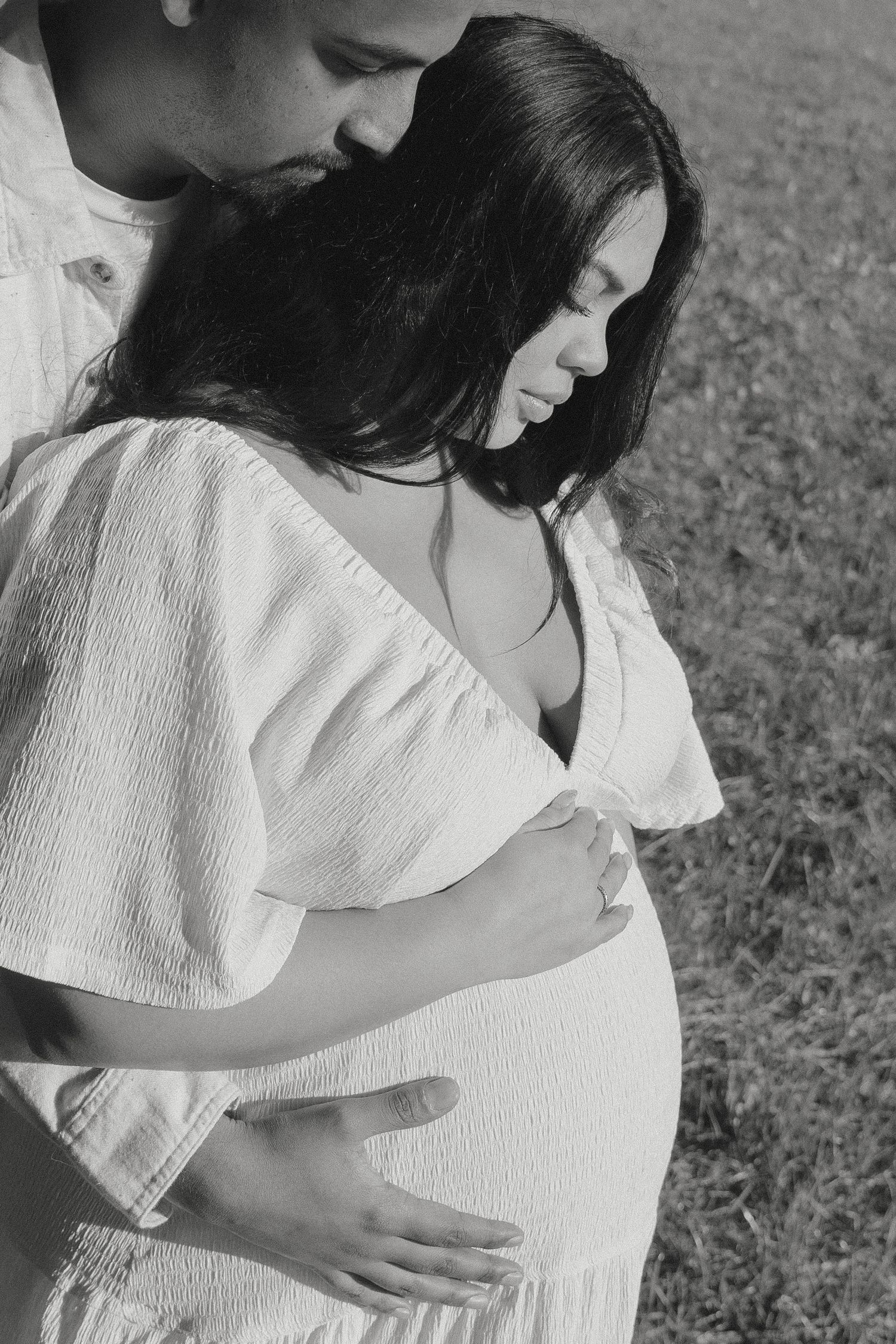 Black and white intimate photo of a couple tenderly embracing, man holding pregnant womans belly outdoors at Vacaville, CA.