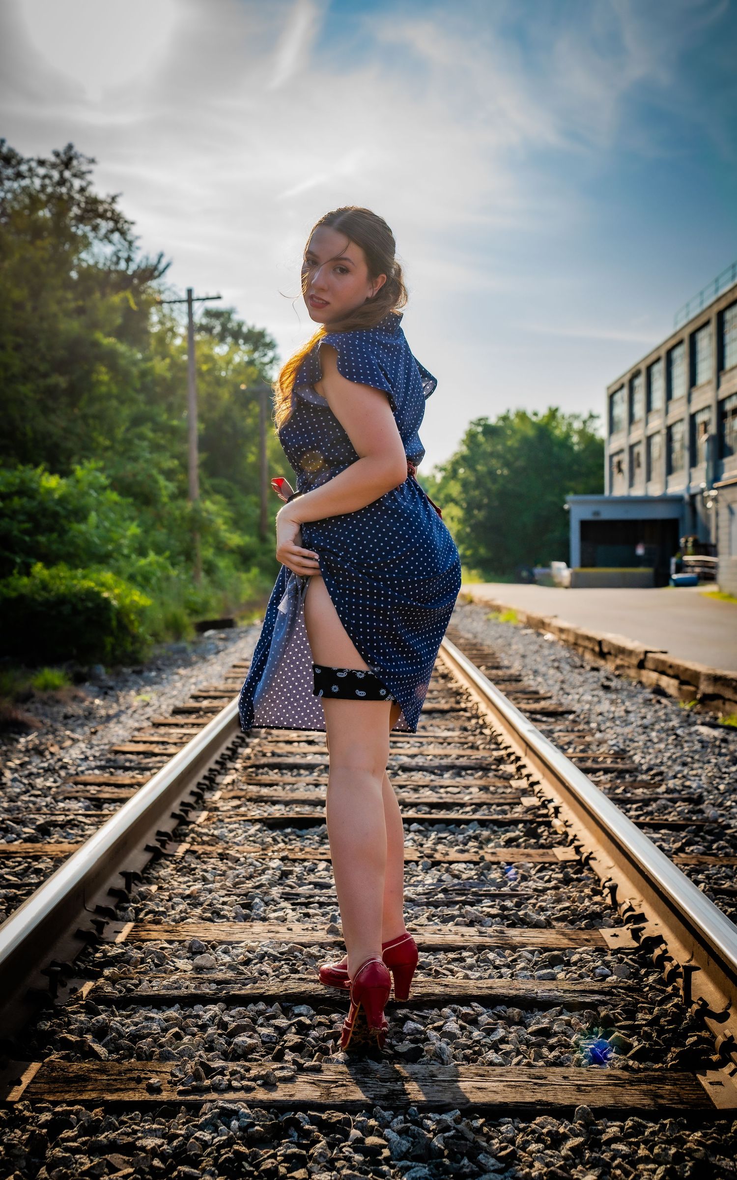 A series of photos showing a child in a polka dot dress and red boots walking along railroad tracks on a sunny day.
