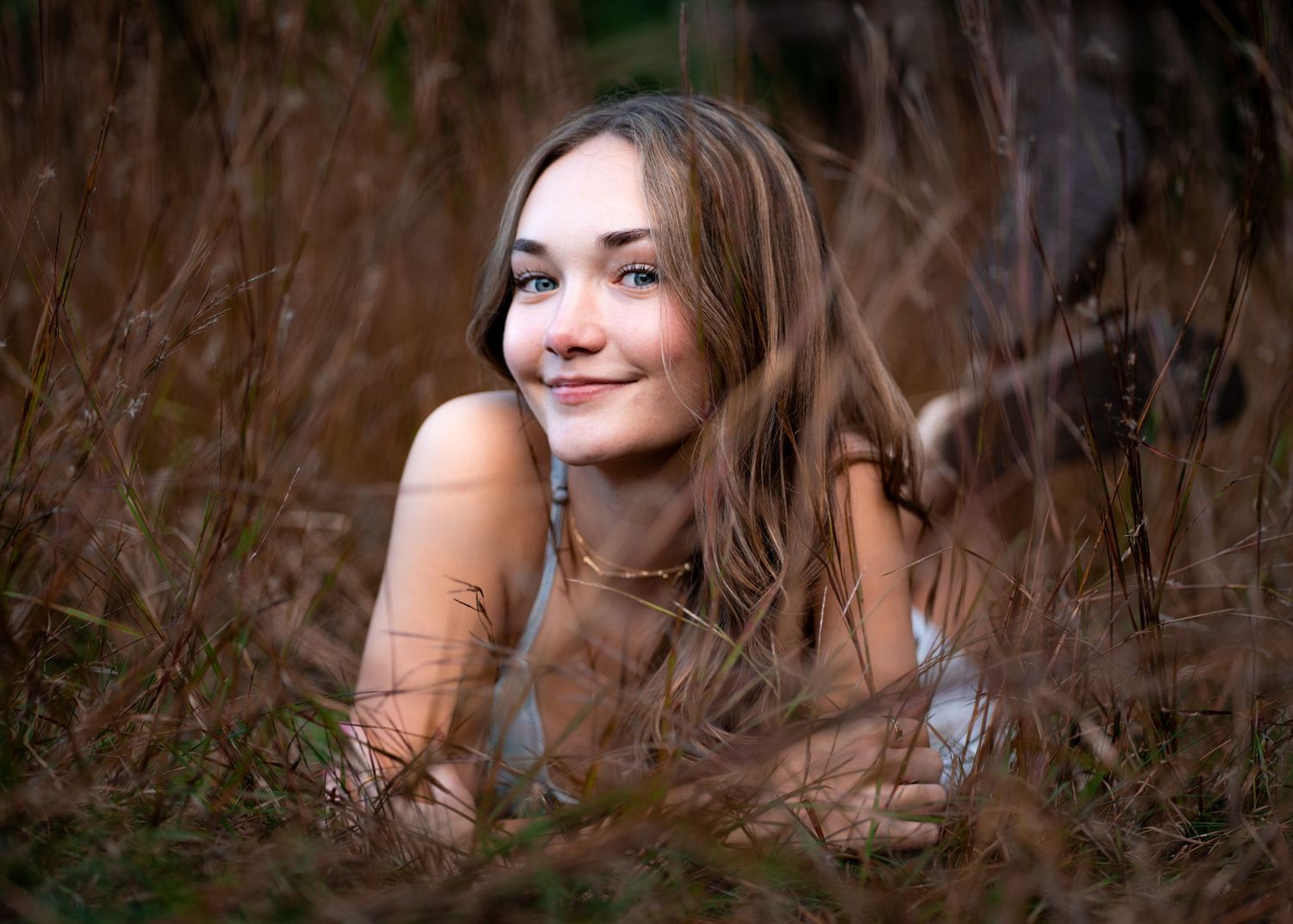Portrait taken through dried autumn grass with soft natural lighting.