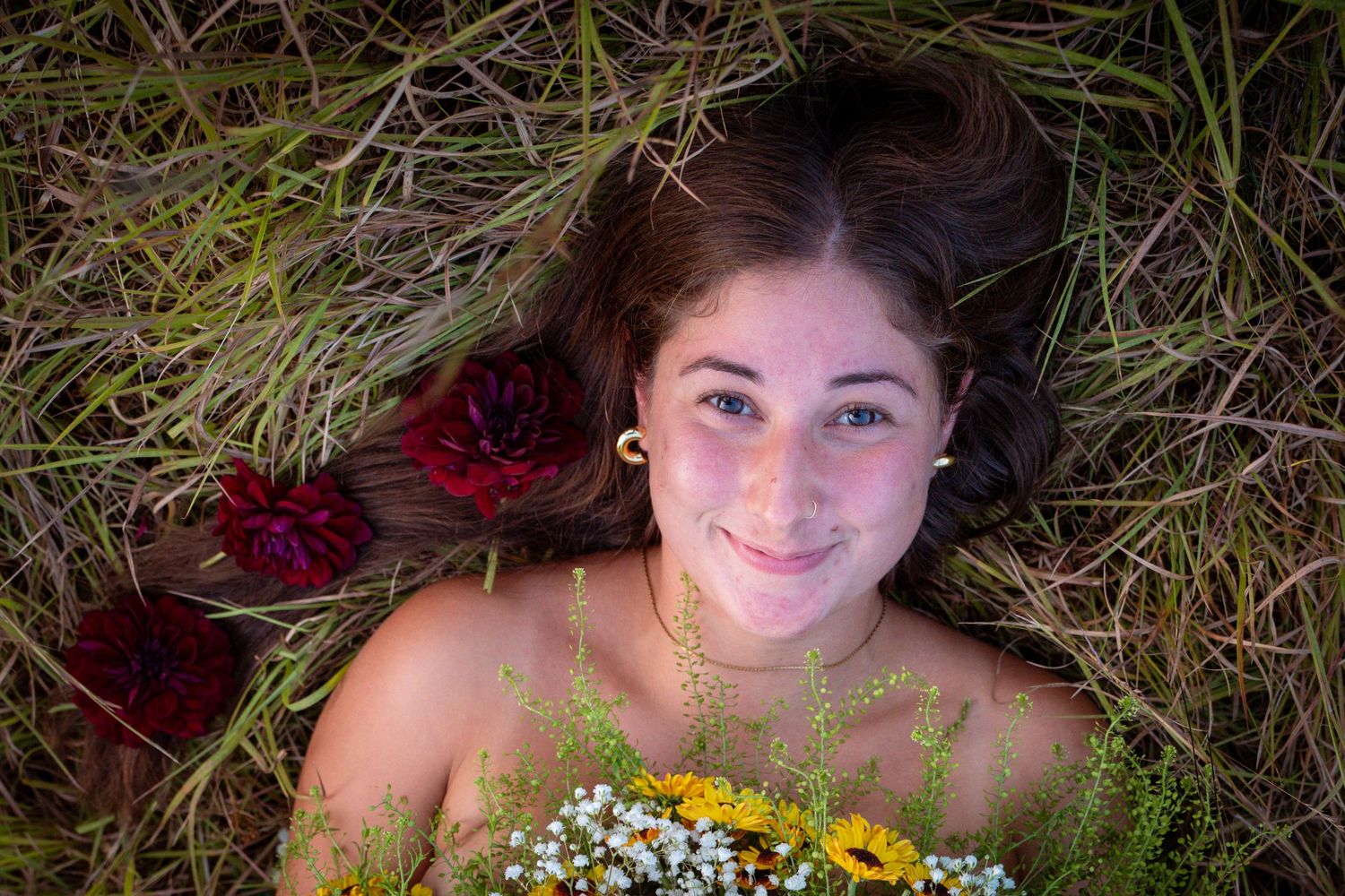 Overhead portrait with wildflowers and red roses in grass.