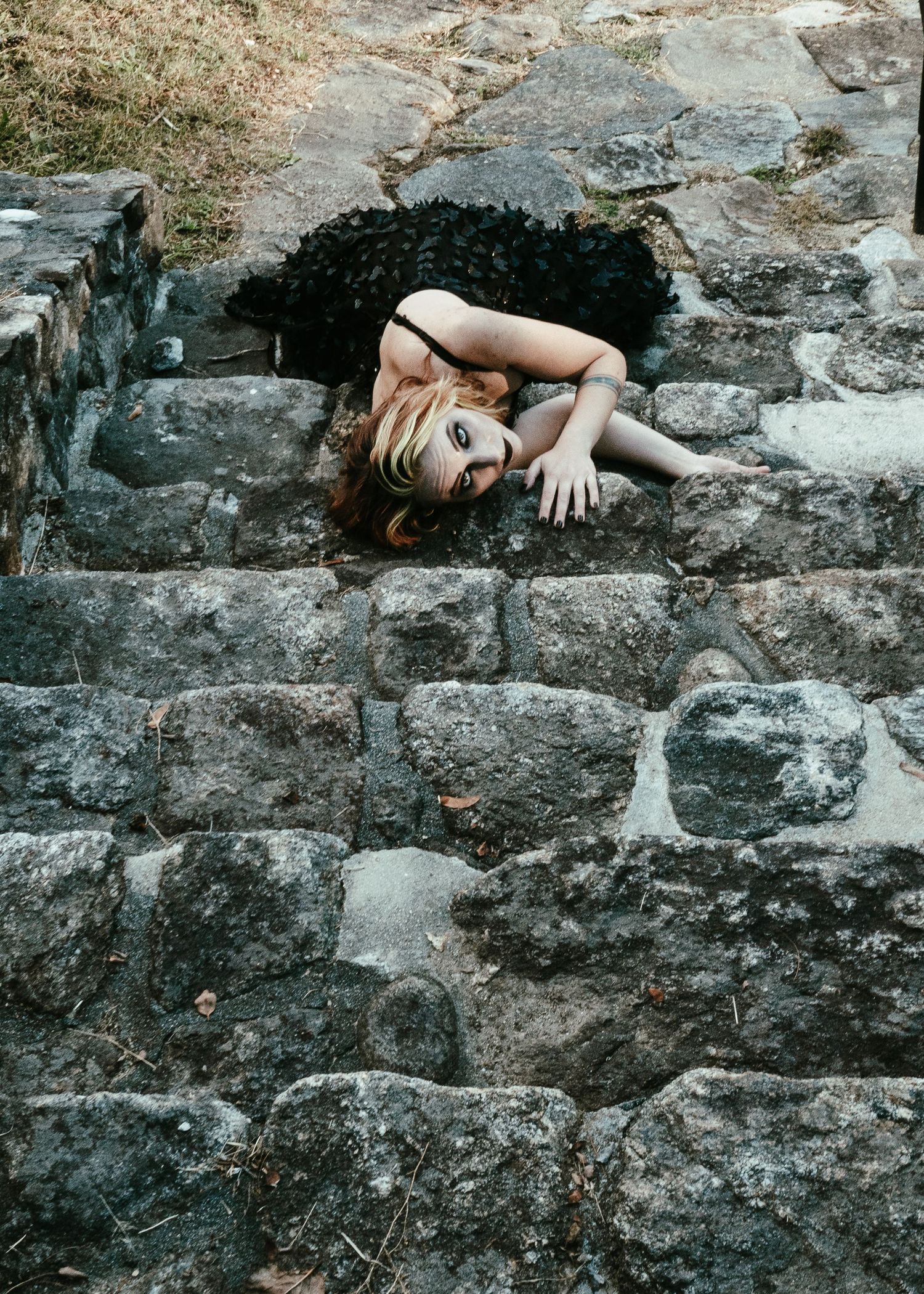 Artistic portrait on stone steps with dramatic lighting and moody atmosphere.