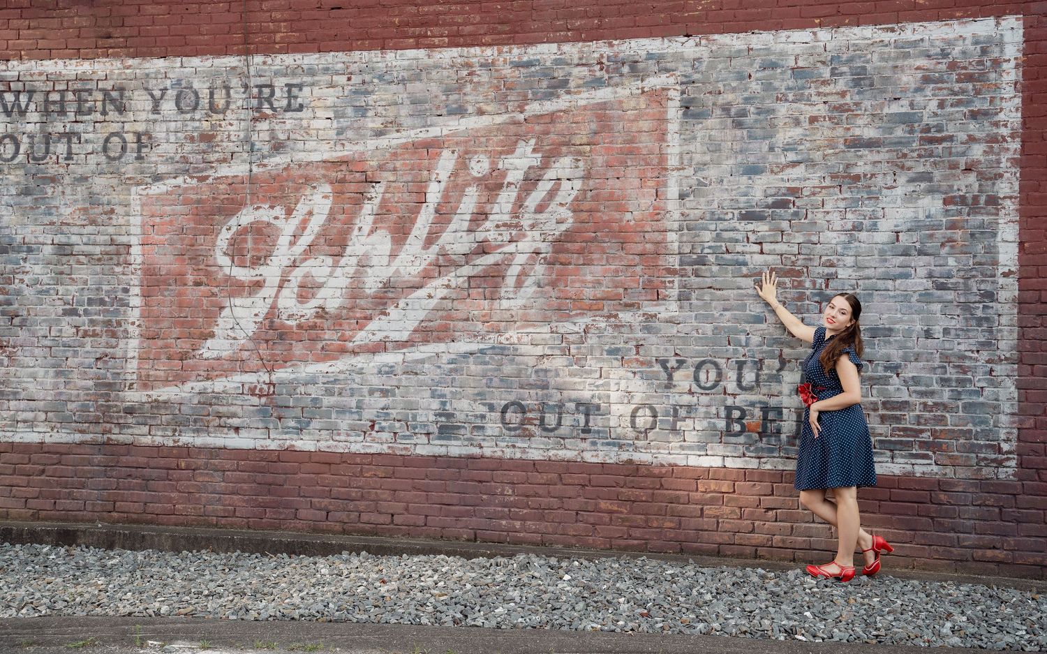 Vintage faded brick wall advertisement with figure standing against urban backdrop.