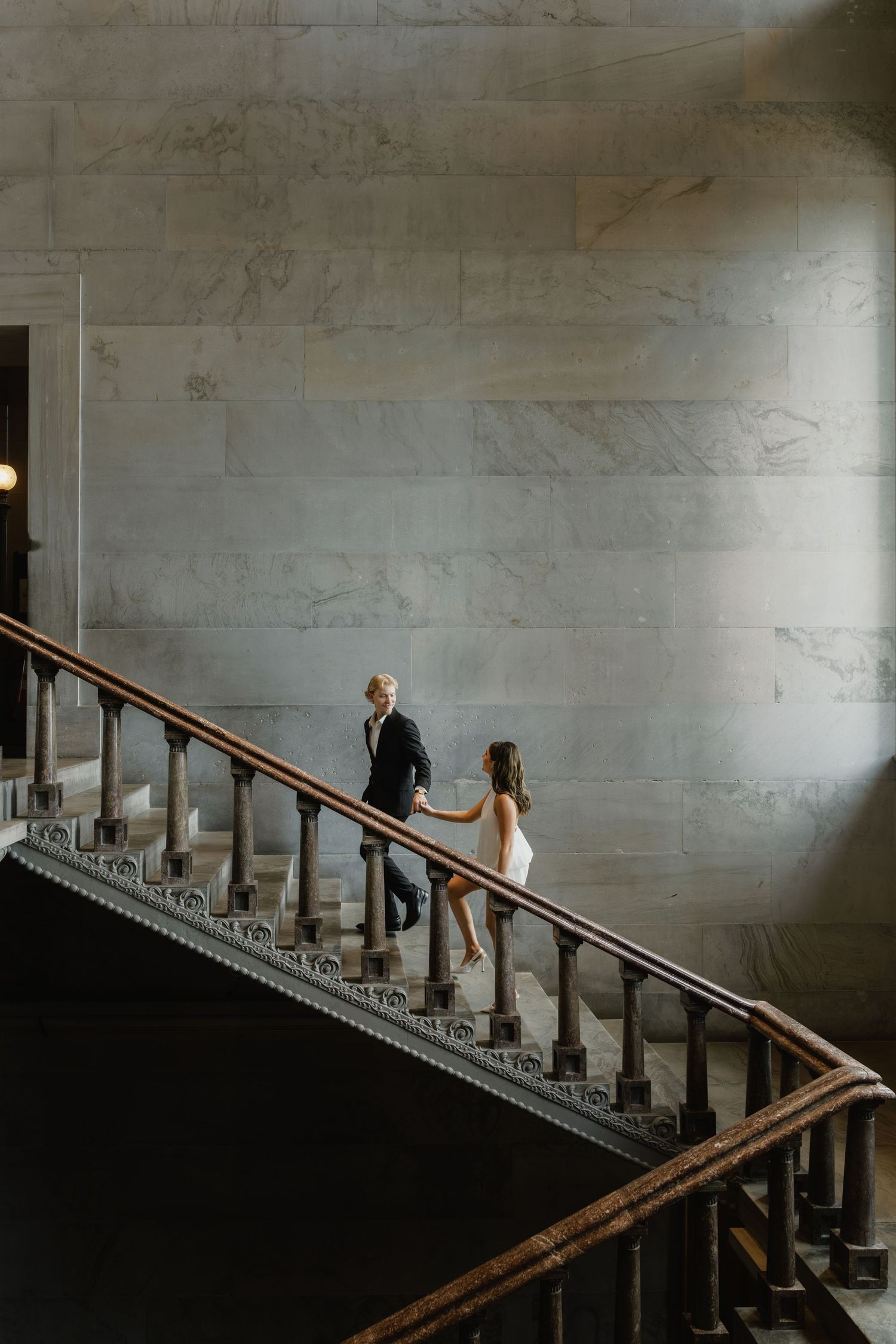 Couple holding hands while walking up ornate marble stairs inside a grand historic building in the Tennessee state capitol engagement.