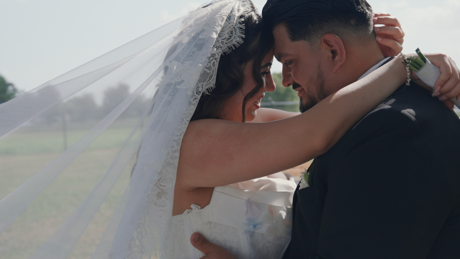 Bride and groom share an intimate forehead touch beneath flowing wedding veil outdoors during a Tennessee wedding in august.