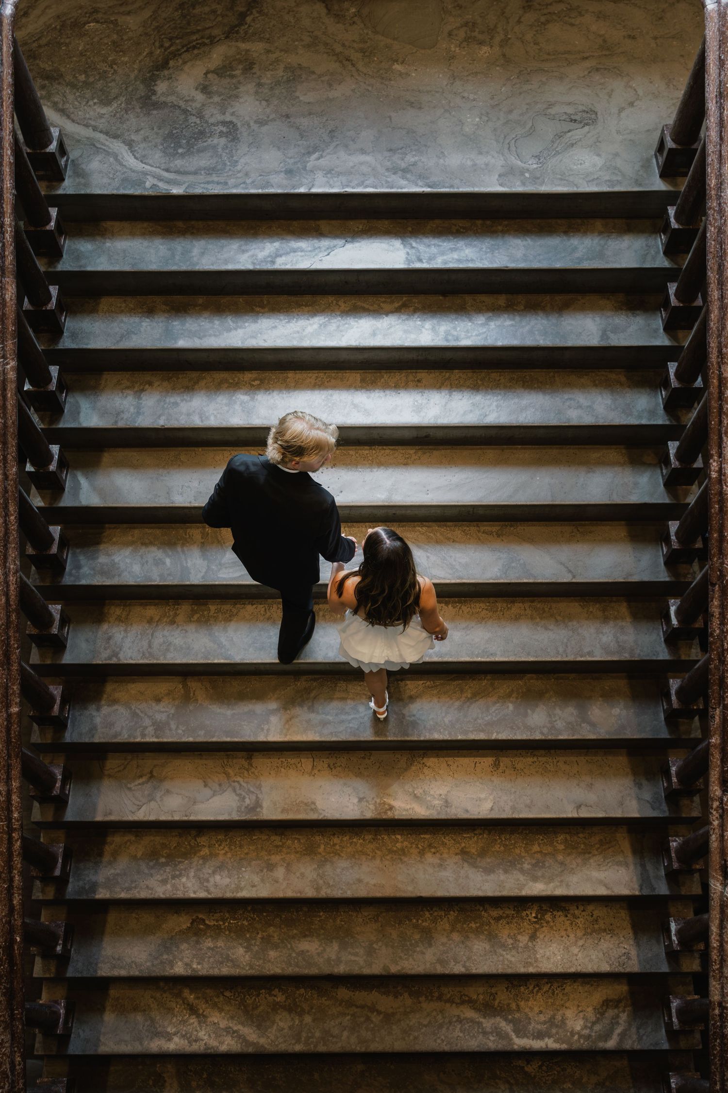 Aerial view of couple walking hand in hand up grand marble staircase in the Tennessee state capital engagement shoot