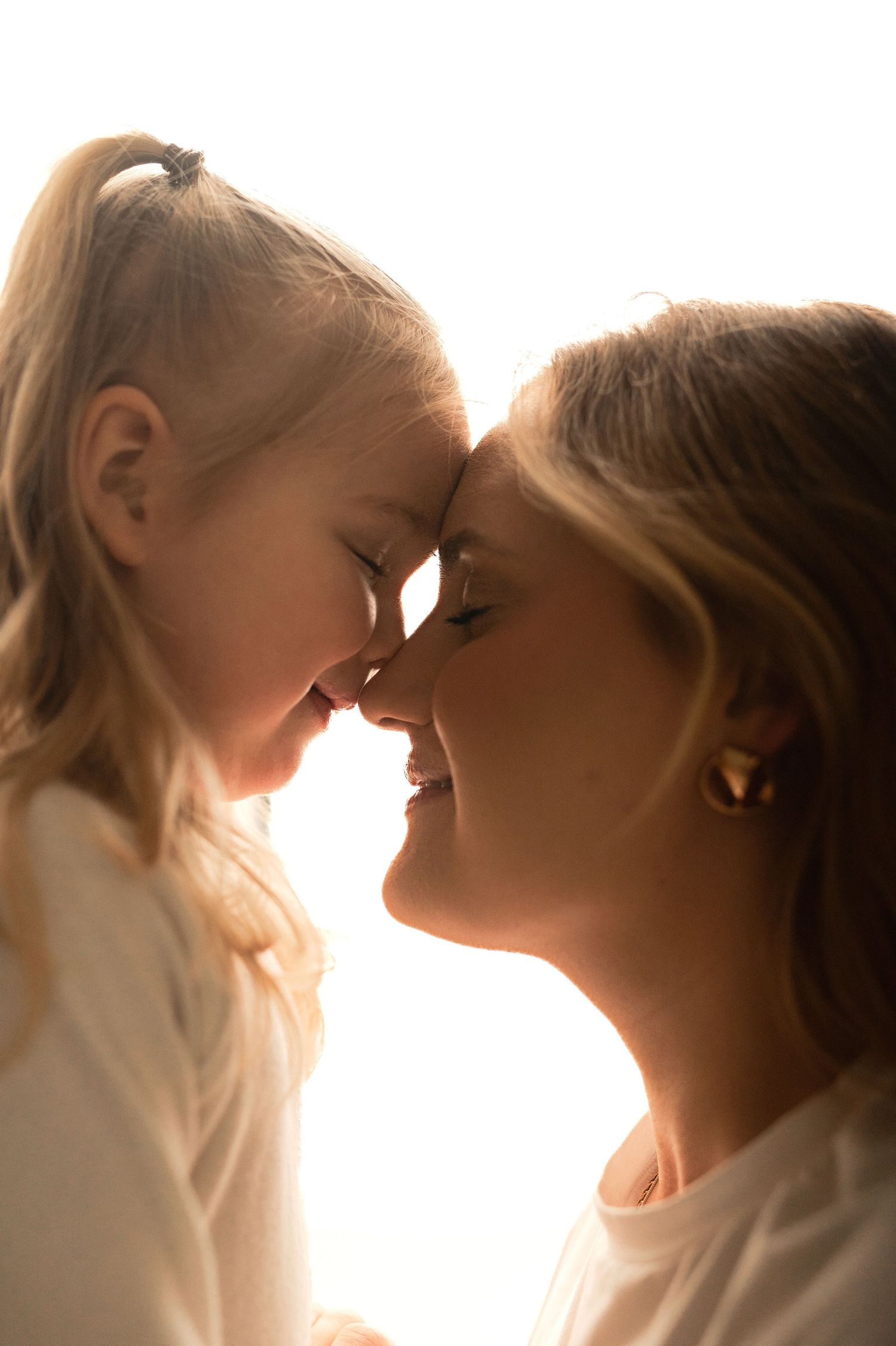 Familjefotografering i Hässleholm med mamma och dotter i varm backlight i studio.