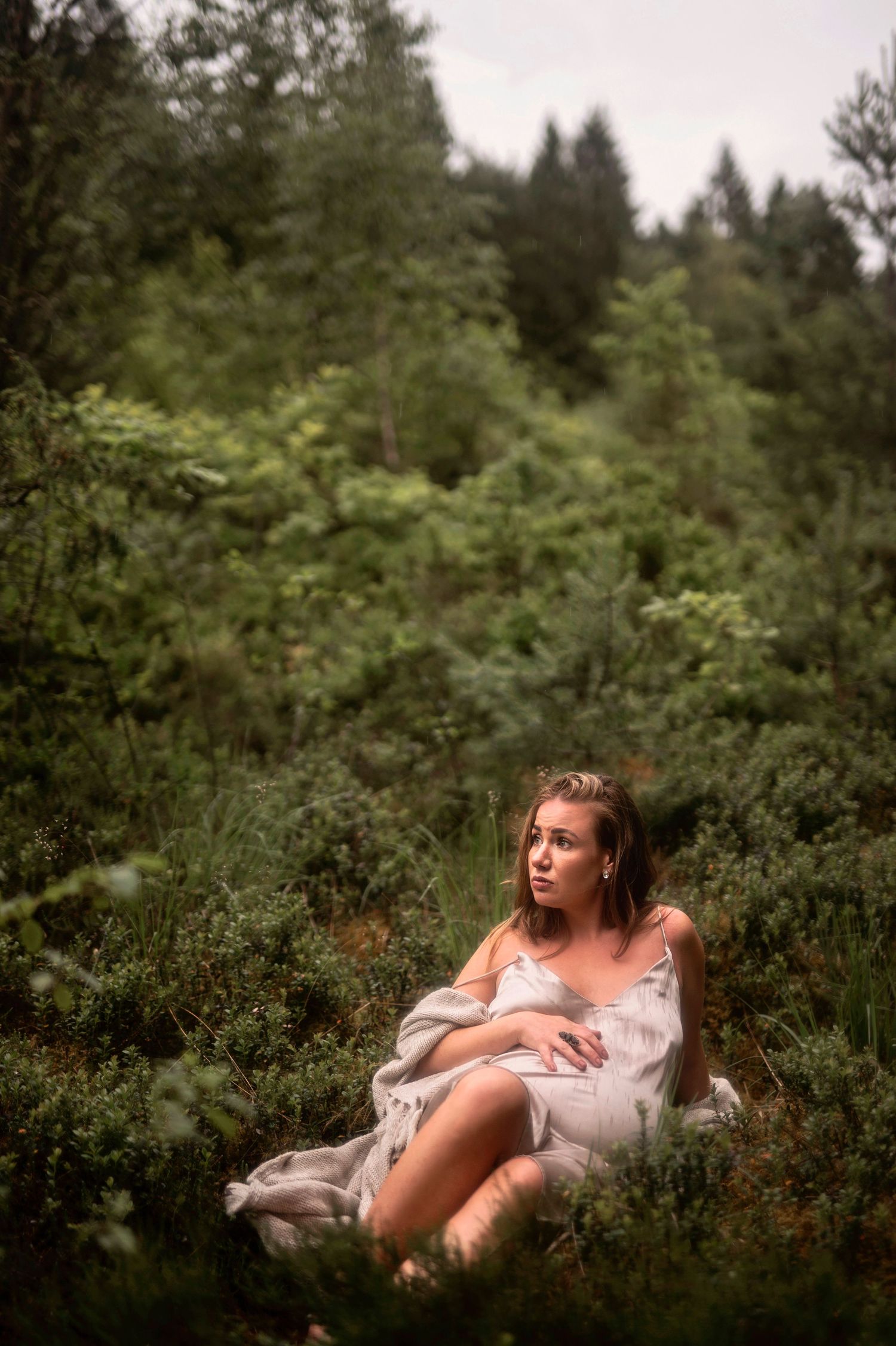 Gravidfotografering i Skåne med gravid kvinna i naturen i regn och moody ljus.