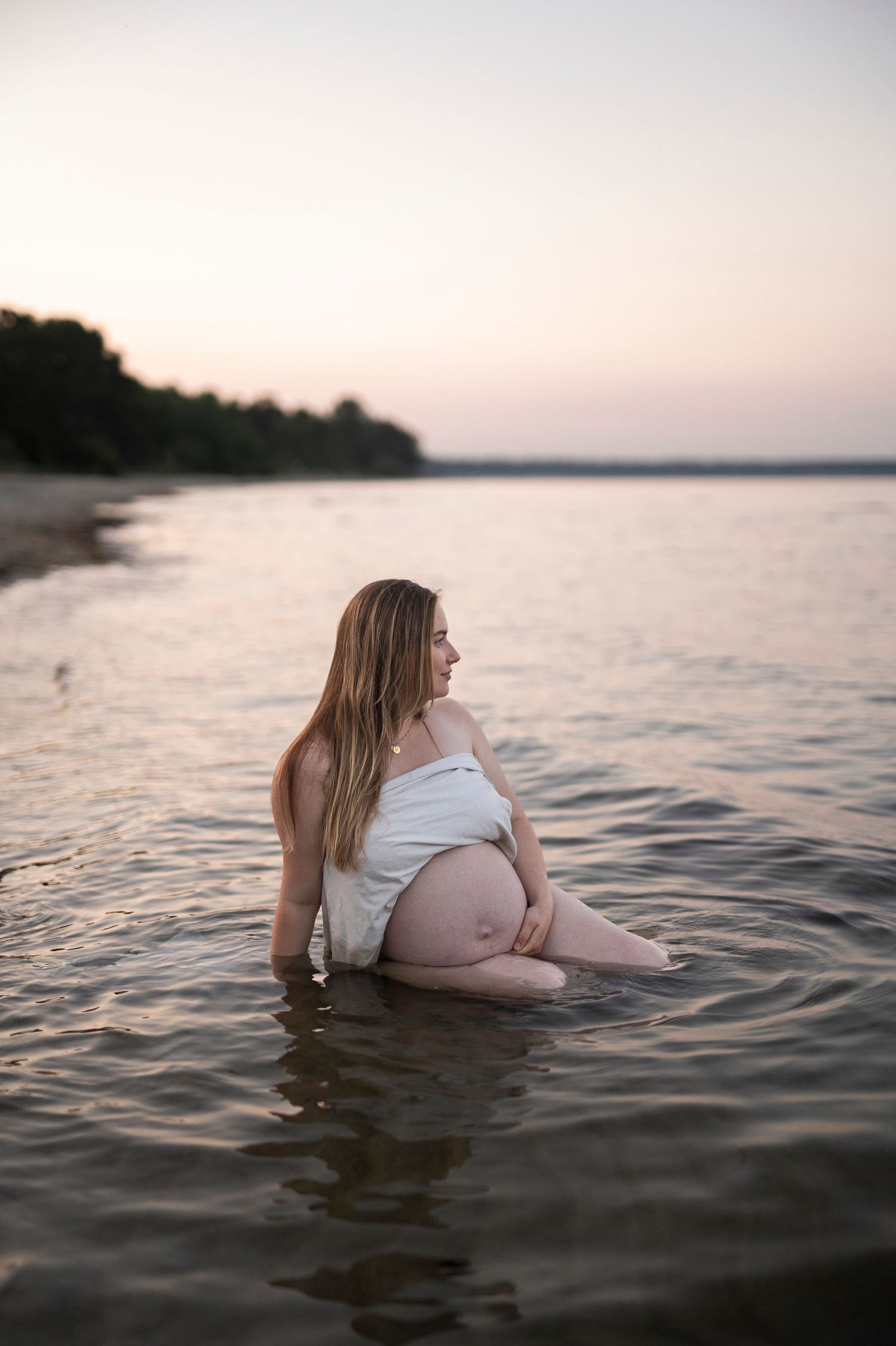 Gravidfotografering i Skåne vid Åhus med blivande mamma i havet vid solnedgång.