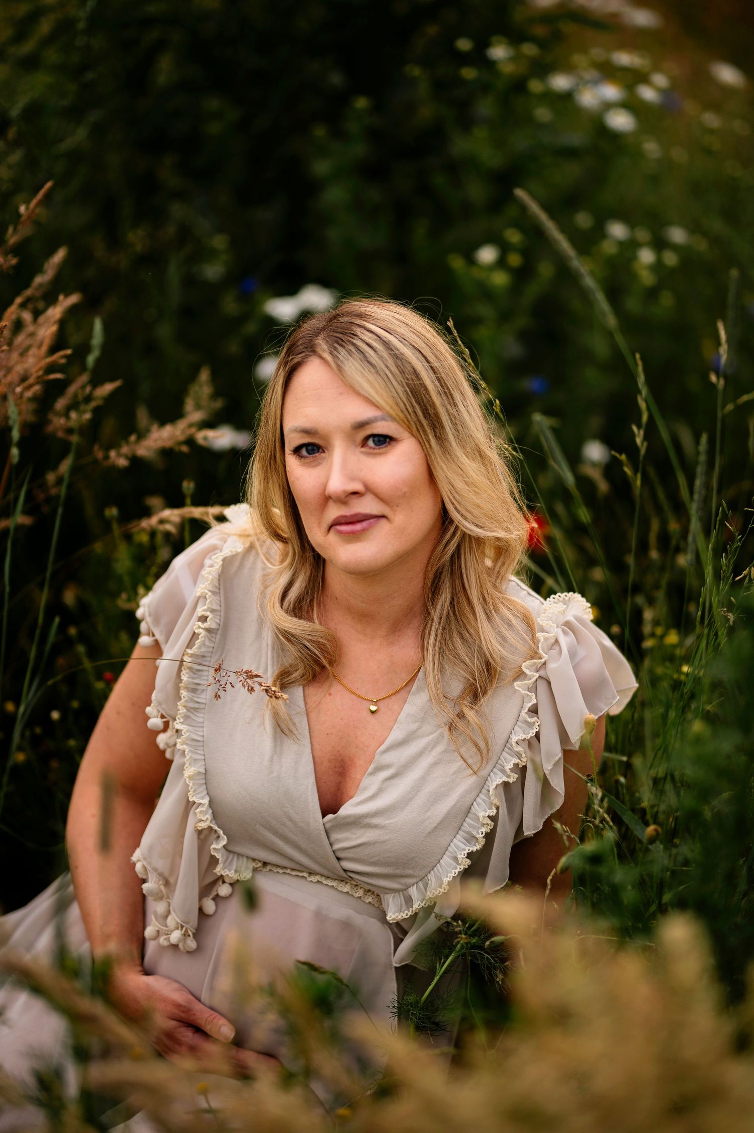 A maternity portrait taken in a summer wildflower meadow with soft natural lighting.