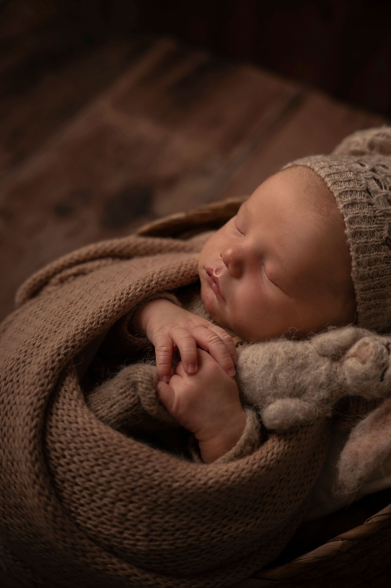 Sovande nyfödd bebis i korg under en nyföddfotografering i Hässleholm i varma jordnära toner.