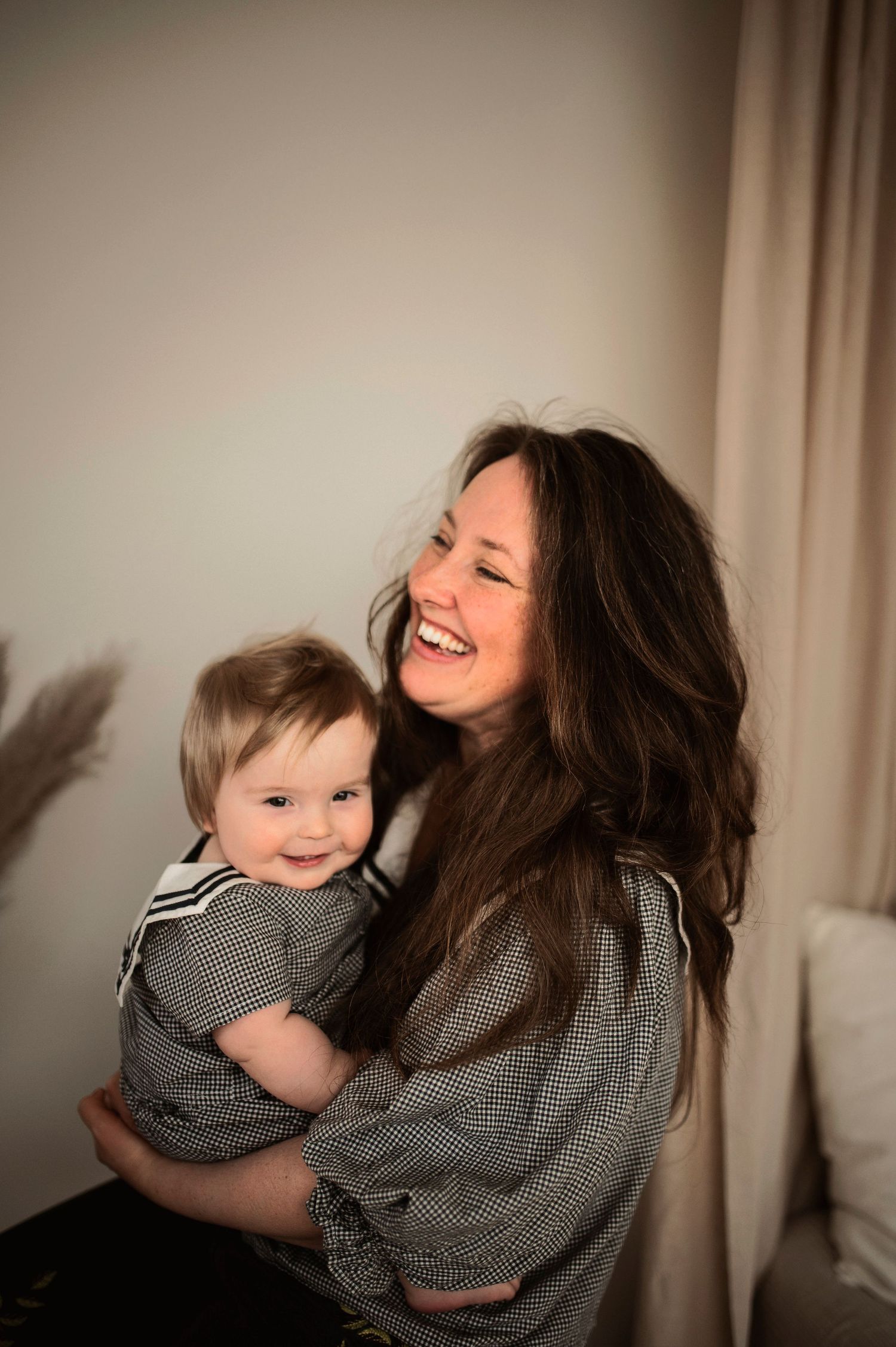 Familjefotografering i Hässleholm med mamma och bebis i mjukt studioljus vid fönster.