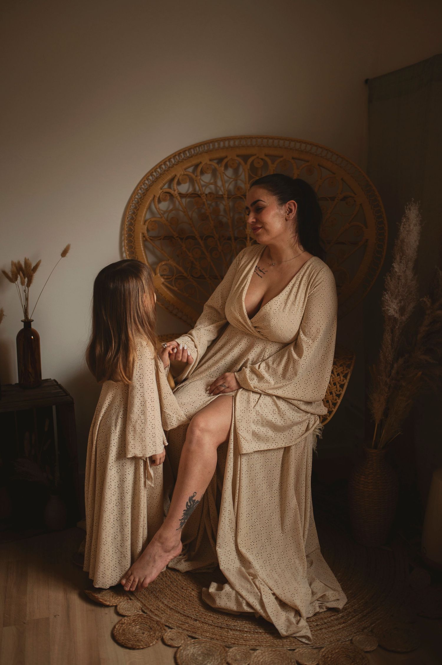 Artistic portrait against ornate rattan chair featuring flowing beige and mauve dresses.