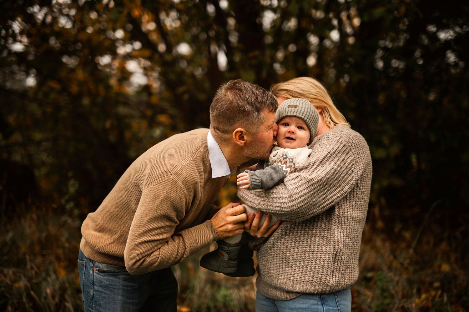 Intimate family moment captured outdoors with cozy sweaters in autumn setting.