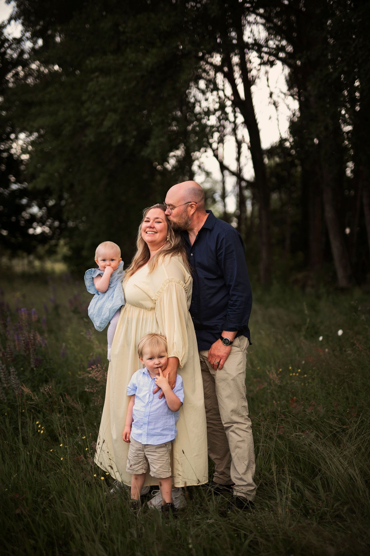 Familjefotografering i Skåne med familj på fyra i blomsteräng i natur i mjukt kvällsljus.