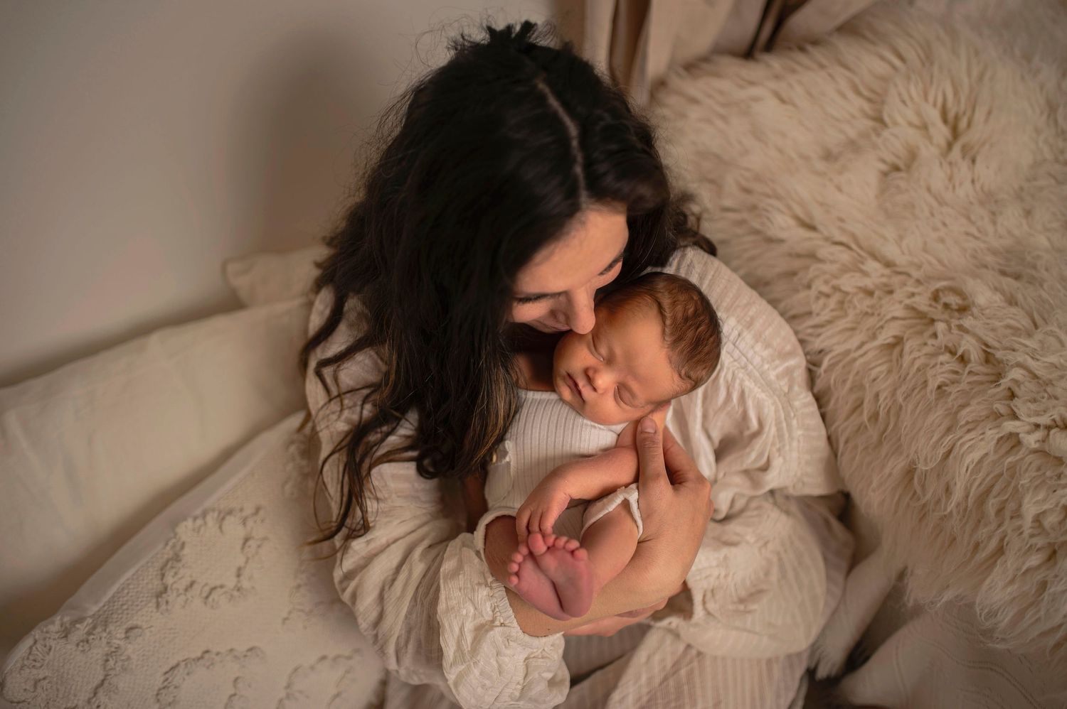 Mamma ser kärleksfullt på sin sovande nyfödda bebis under en nyföddfotografering i Hässleholm.