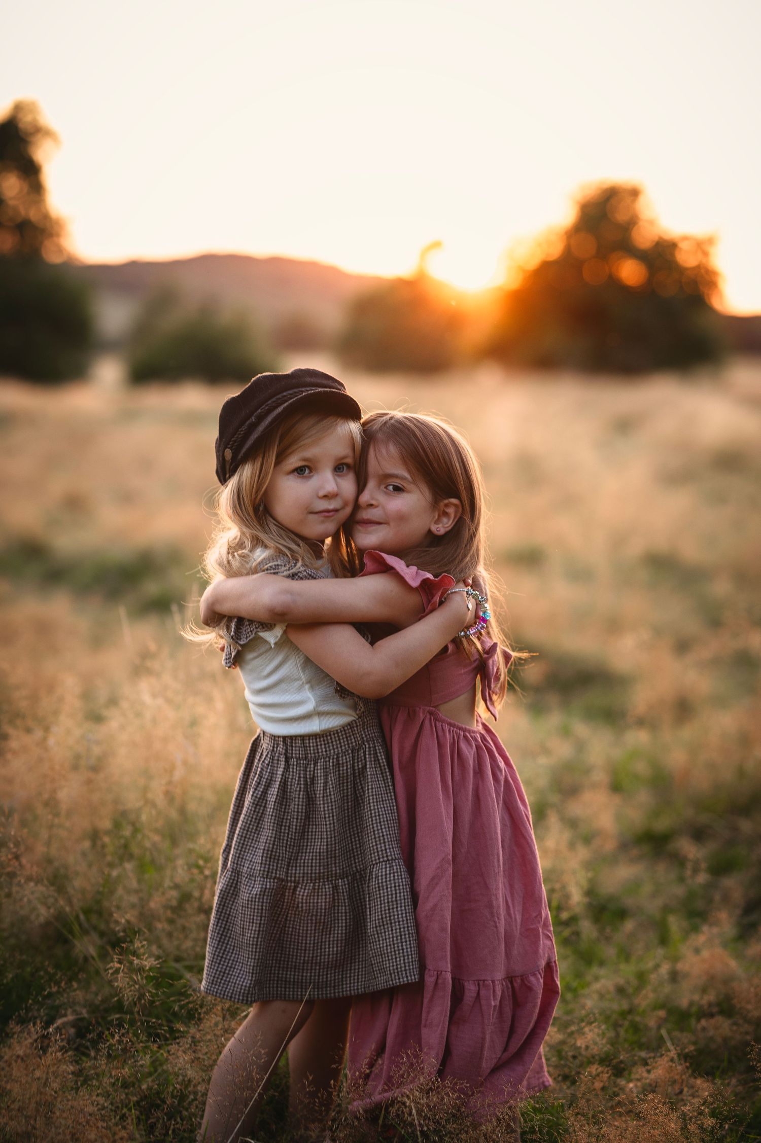 Sweet moment between two children hugging in golden sunset field.