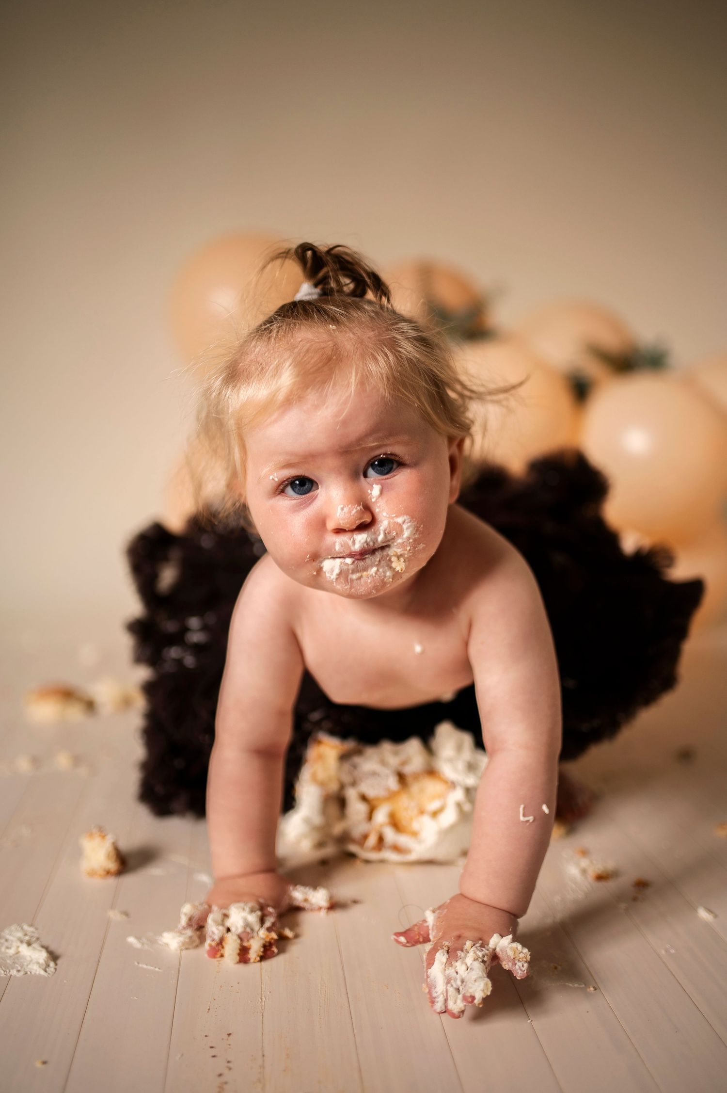Smash the cake-fotografering i Hässleholm med en bebis i svart tyllkjol och grädde i ansiktet.