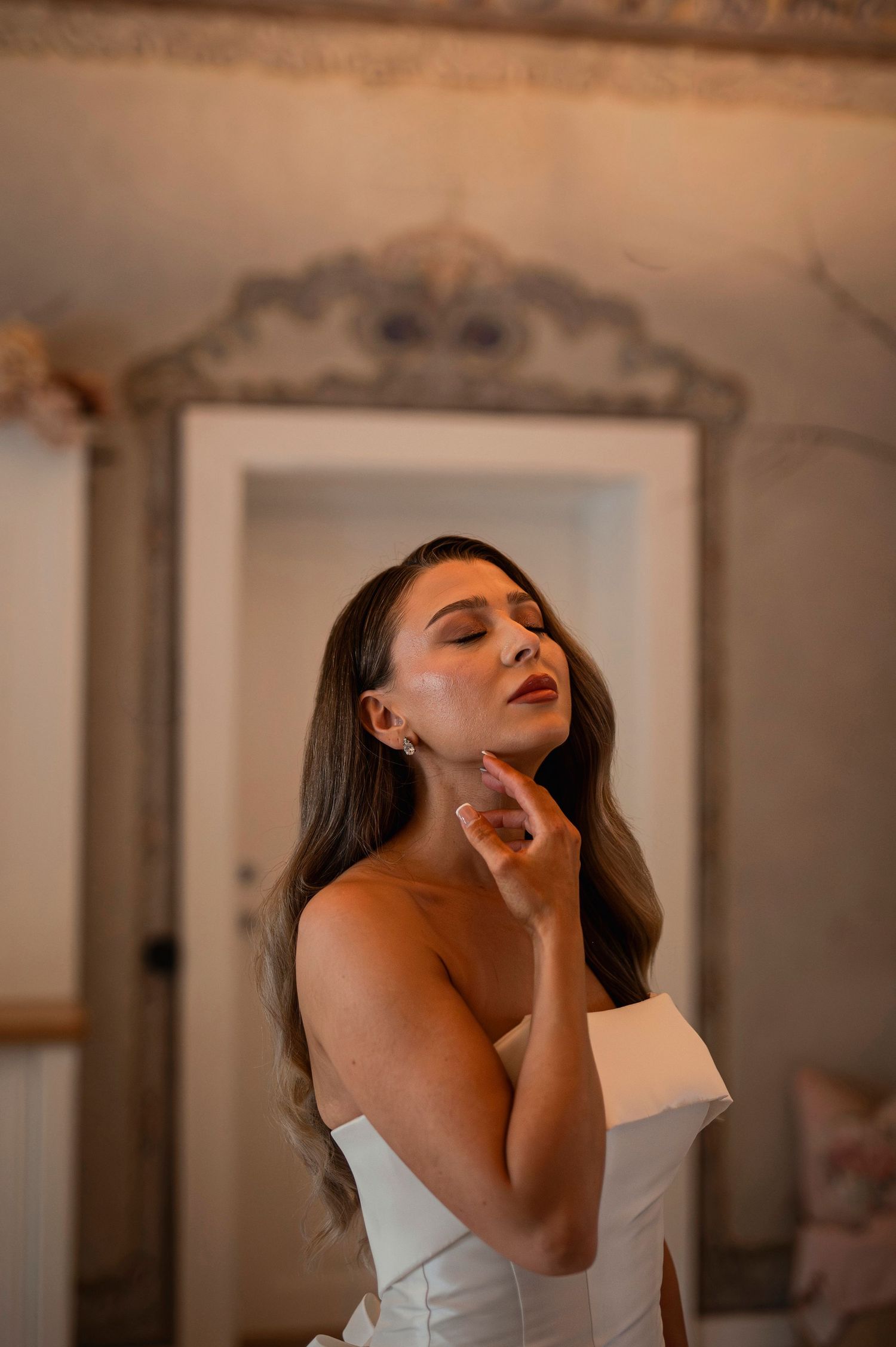 Bröllopsfotografering på Norrviken i Skåne med brud i elegant klänning vid vintage spegel i varmt ljus.