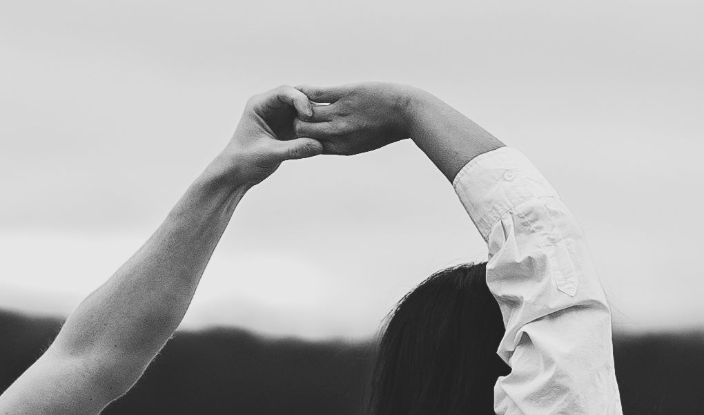 Close-up of raised hands forming an arch against a blurry background.