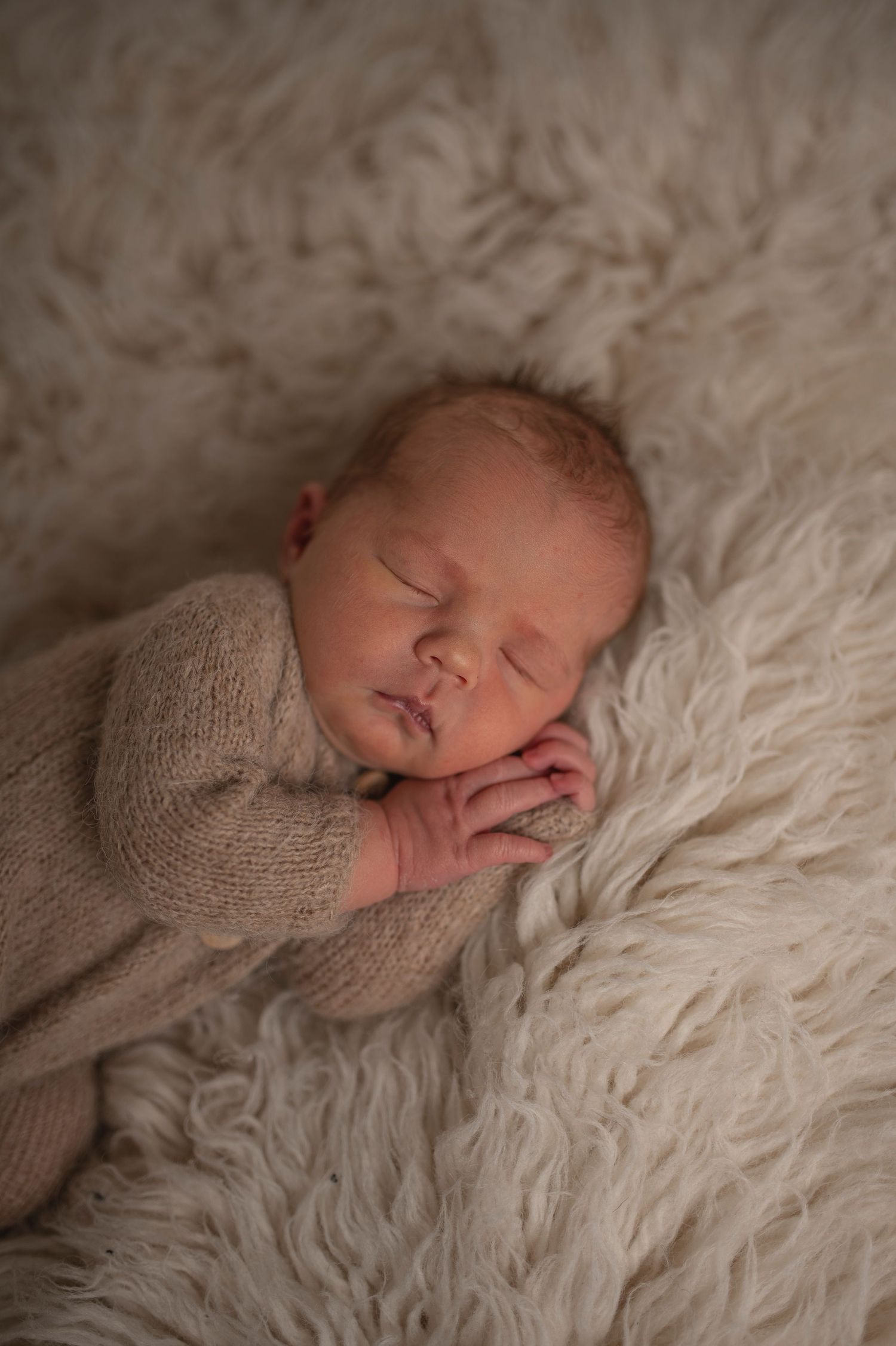 Sovande nyfödd bebis fotograferad under en nyföddfotografering i Hässleholm i mjuka beige toner.