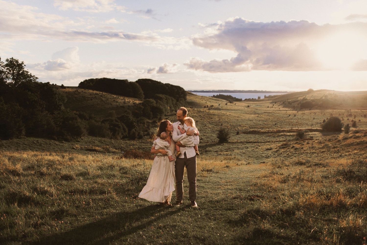 Familjefotografering i Skåne på Hilleshögs Dalar med familj i solnedgång över landskap.