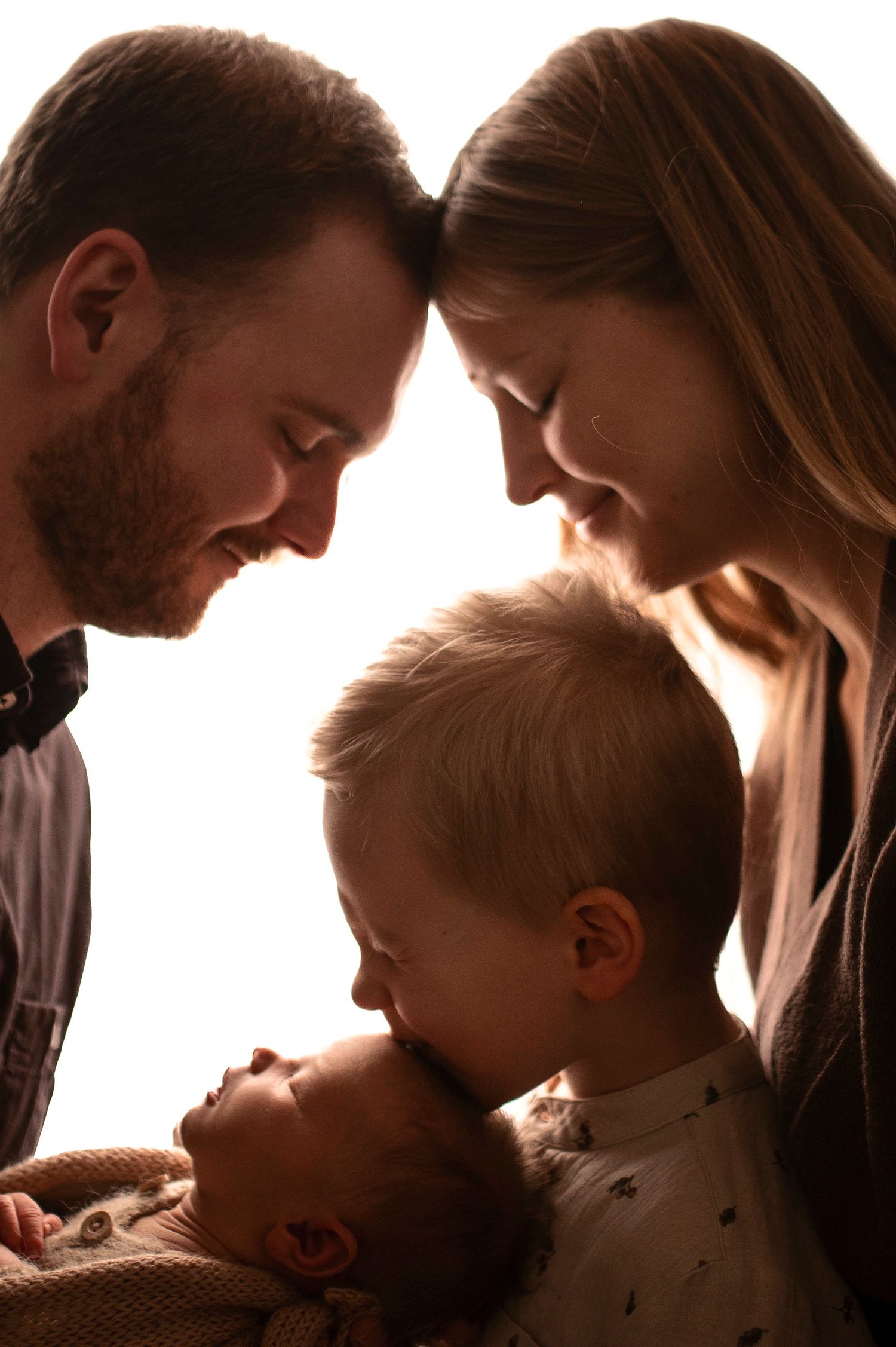 Familj med syskon och nyfödd bebis under en familjefotografering i Hässleholm i mjukt ljus.