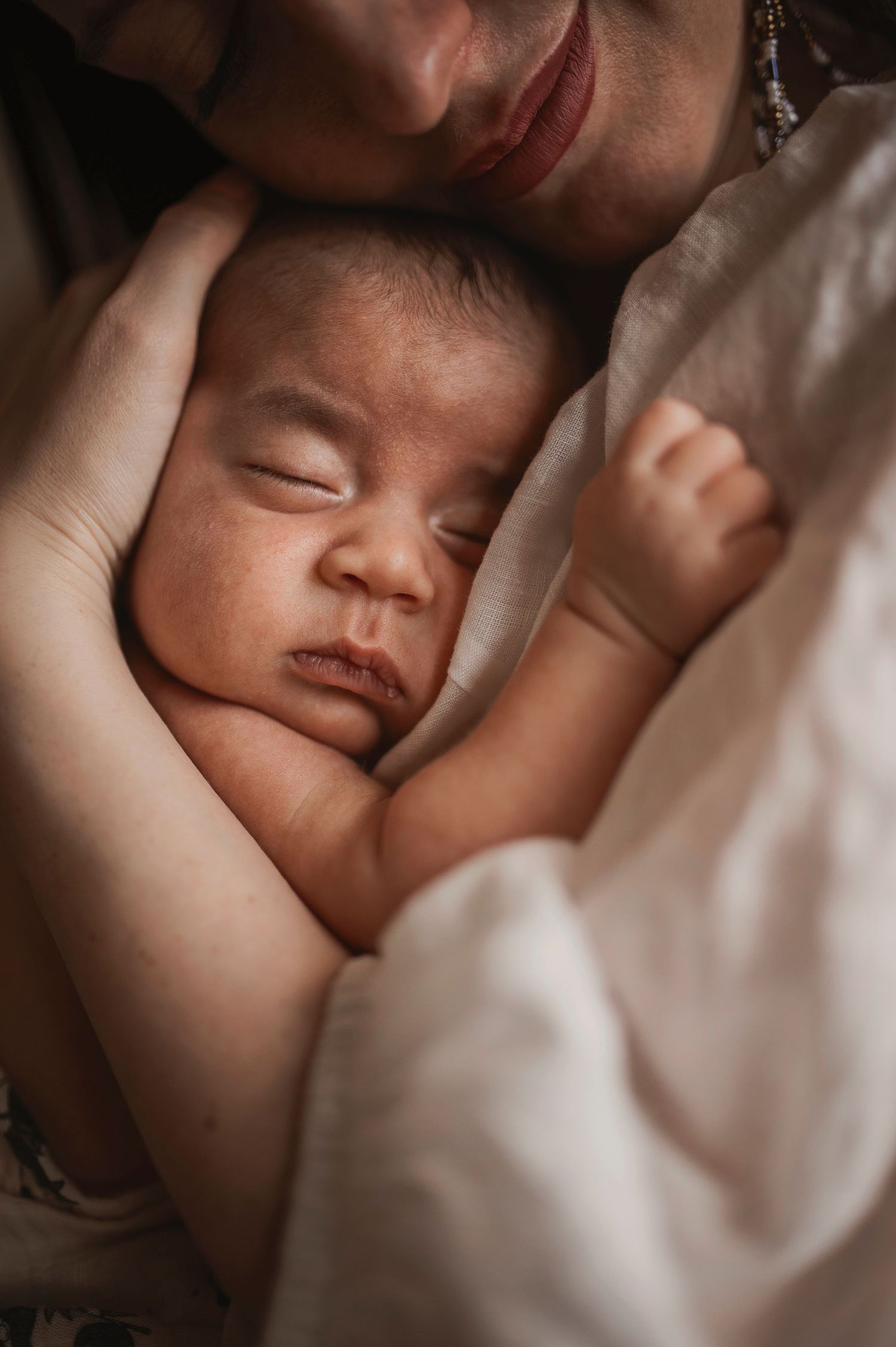 A sleeping infant nestled in soft blankets with gentle lighting creating an intimate mood.