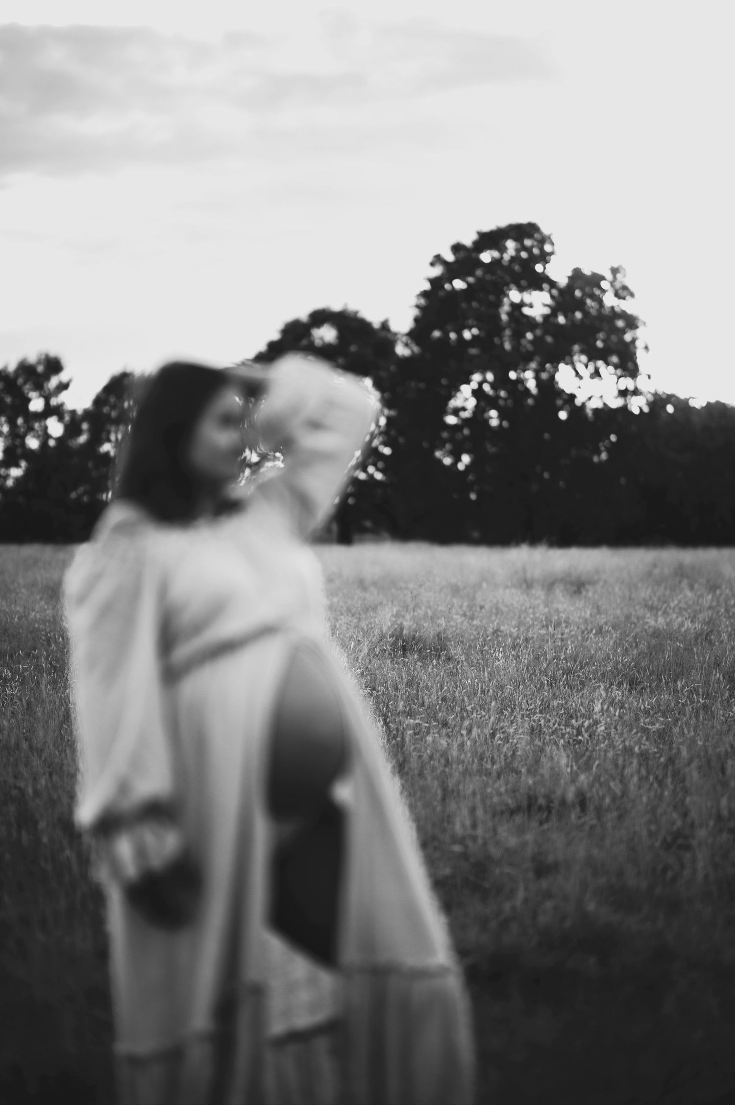An artistic black and white maternity portrait shot in a meadow.