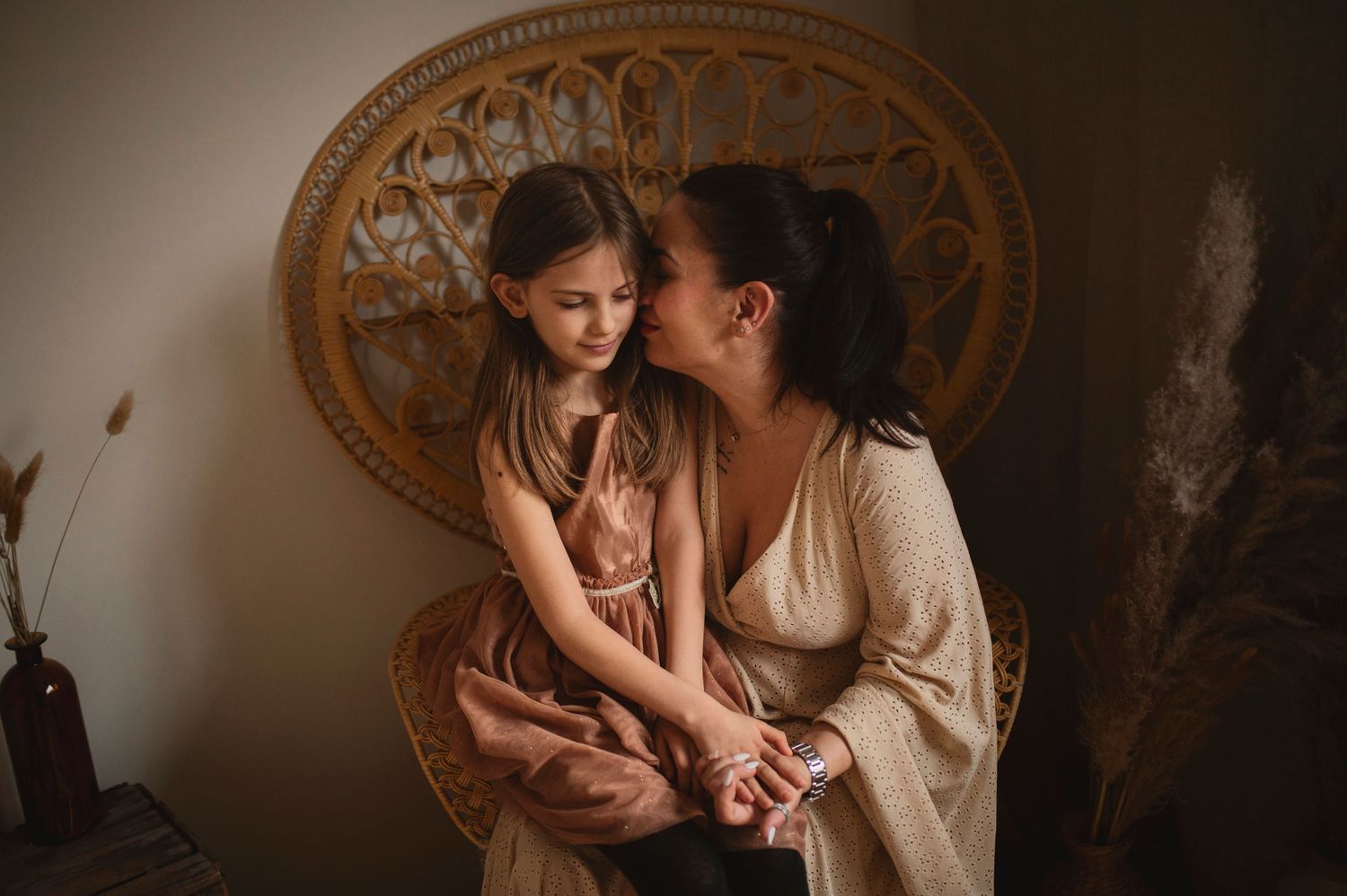 Intimate indoor portrait showcasing warmth and connection against vintage rattan decor.