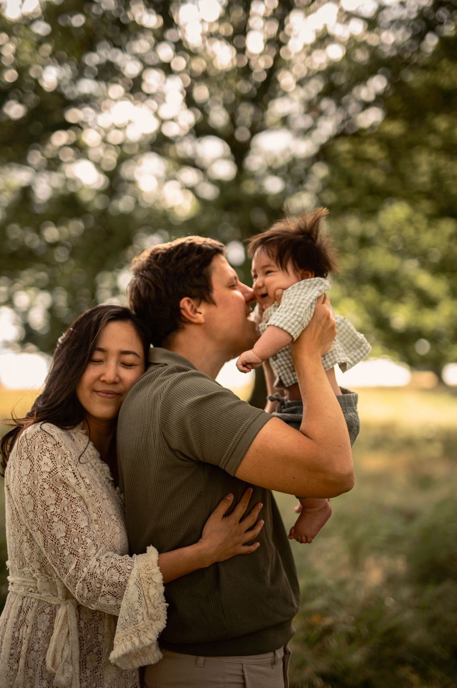 Familjefotografering i Skåne med föräldrar och bebis i kärleksfullt ögonblick i utomhusmiljö.