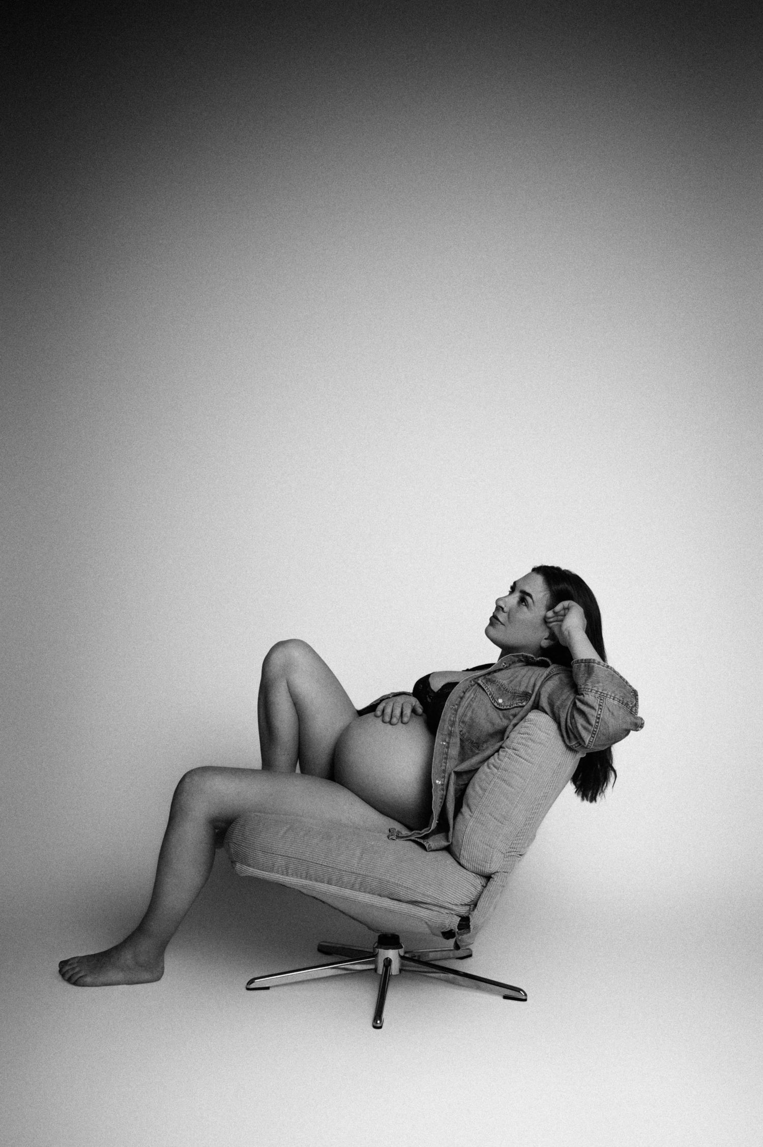 Svartvit gravidfotografering i Hässleholm med gravid kvinna i studioporträtt i klassisk stol.