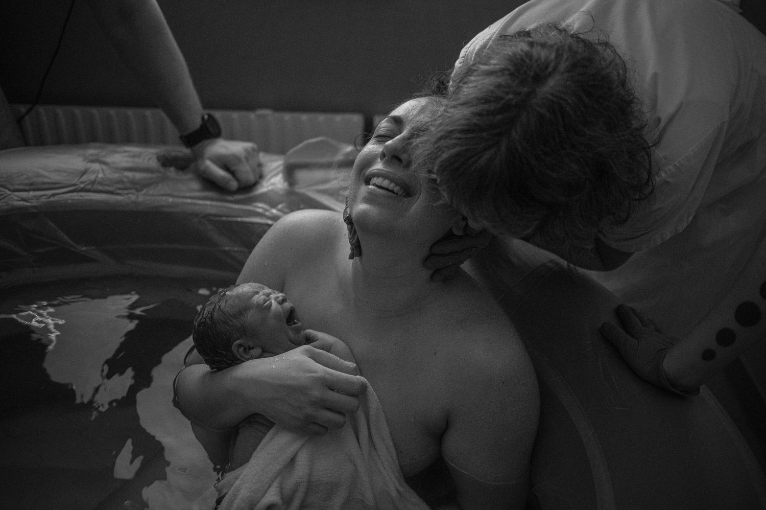 Black and white photograph capturing the intensity of childbirth in a medical setting.