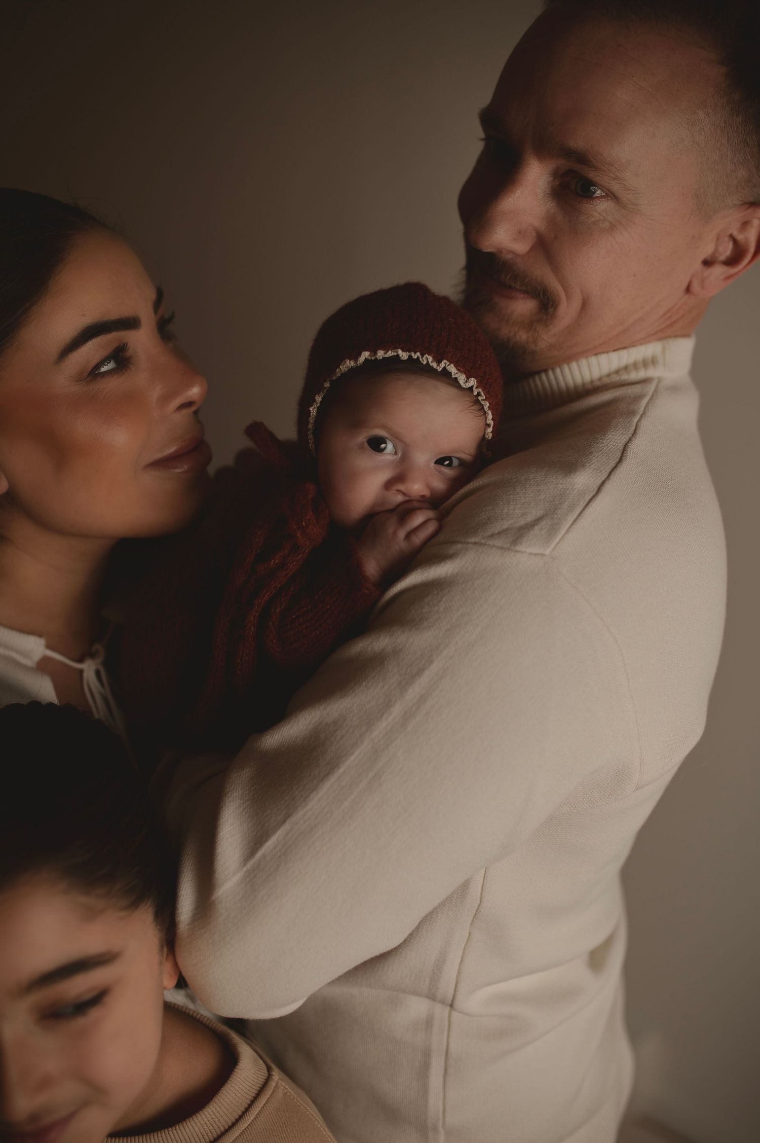 Cozy family portrait in neutral colors with baby in burgundy.