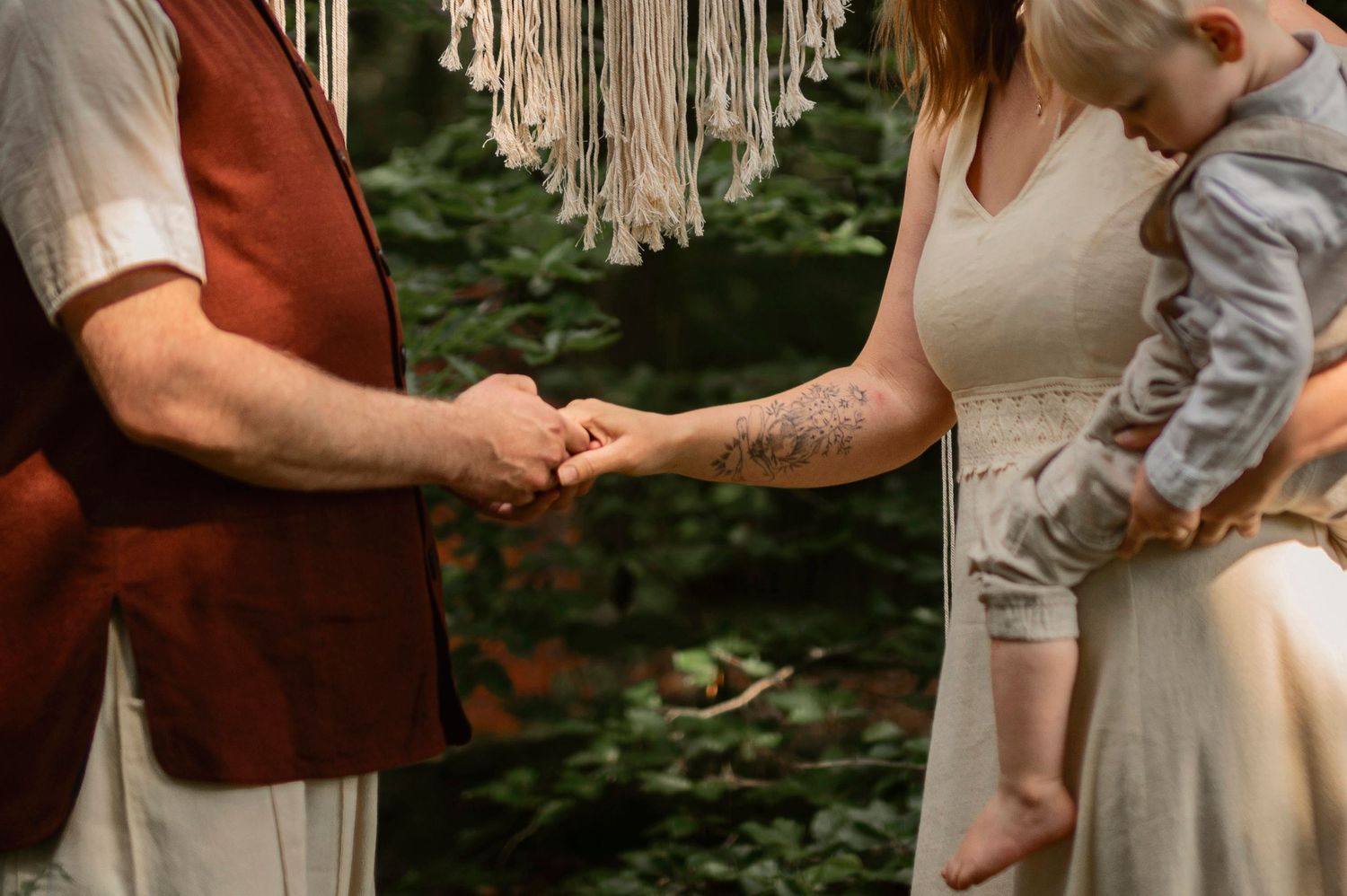 Bride and groom holding hands during a romantic outdoor elopement ceremony in Sweden with their child present.