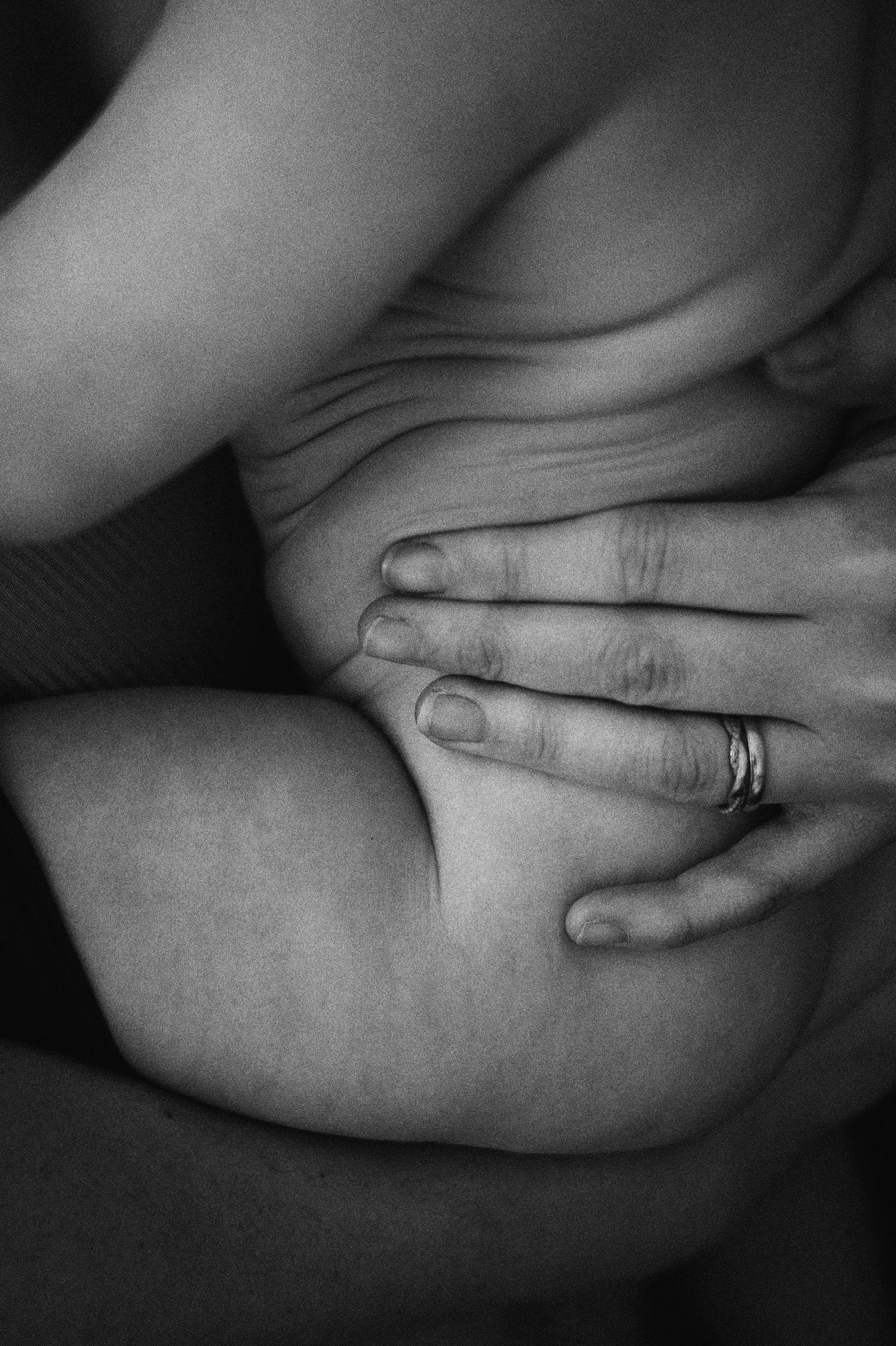 Svartvit nyföddfotografering i Hässleholm med detaljbild av mamma och nyfödd bebis i nära kontakt.