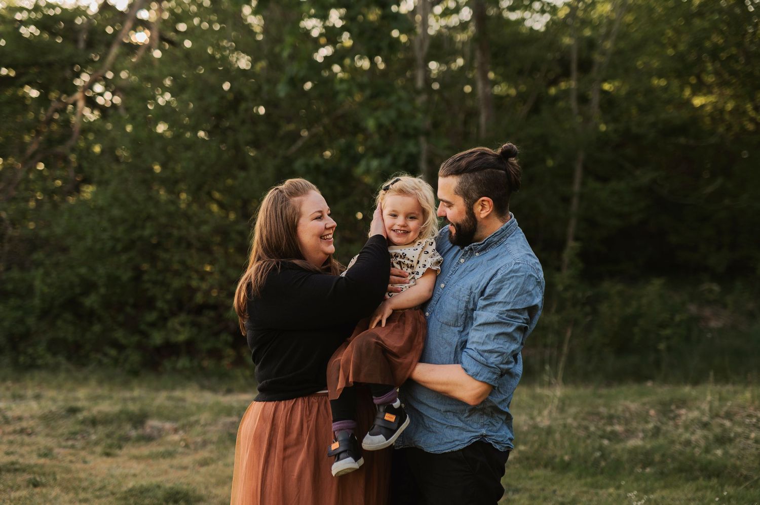 A joyful family moment captured outdoors during golden hour in a natural setting.