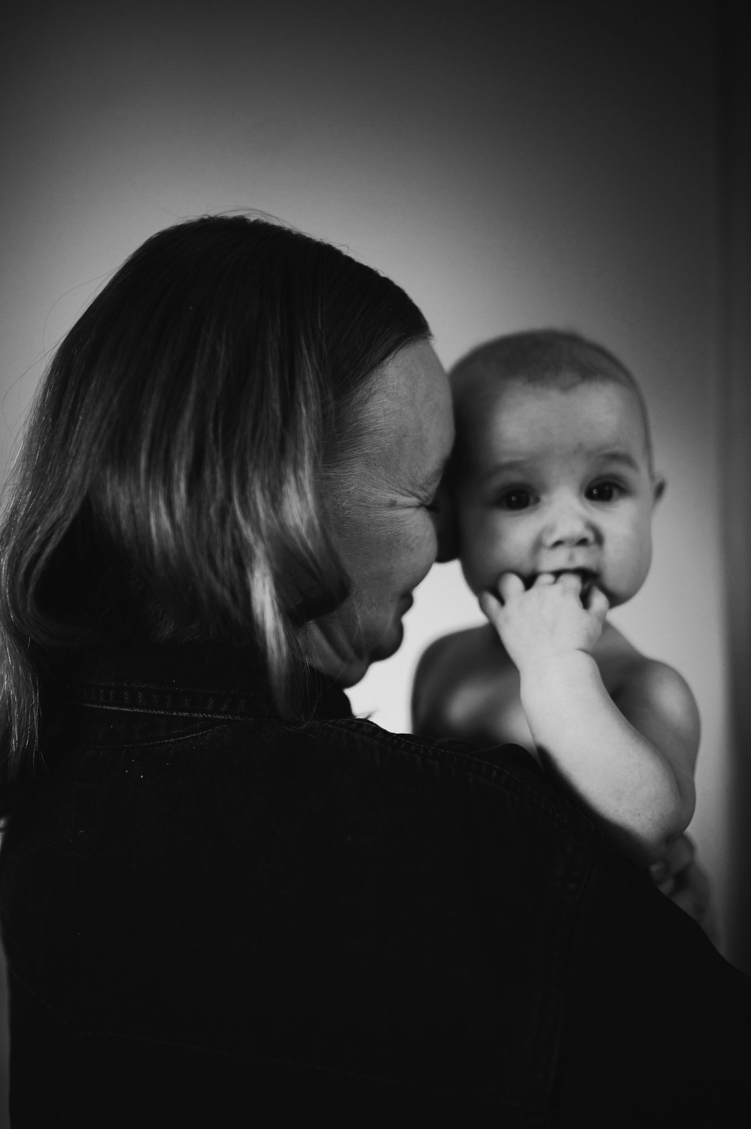 Familjefotografering i Hässleholm med mamma och leende bebis i en varm och kärleksfull stund i studio.