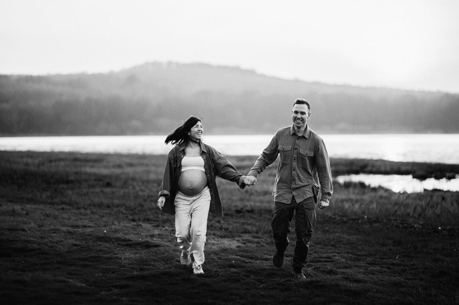 Svartvit parfotografering i Skåne med ett par som promenerar och omfamnar varandra i naturen