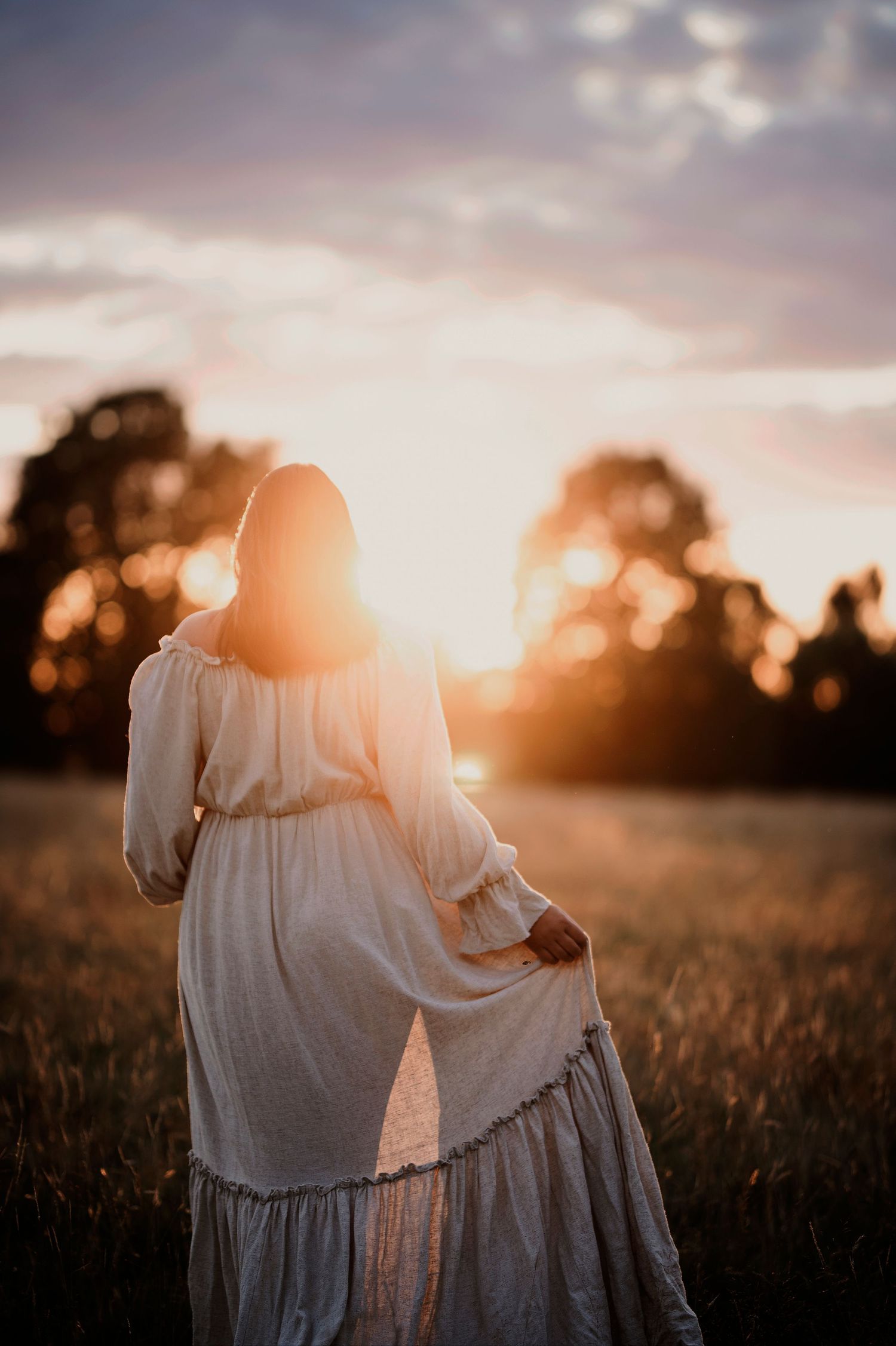 A backlit silhouette of a flowing white dress against a pink sunset sky.
