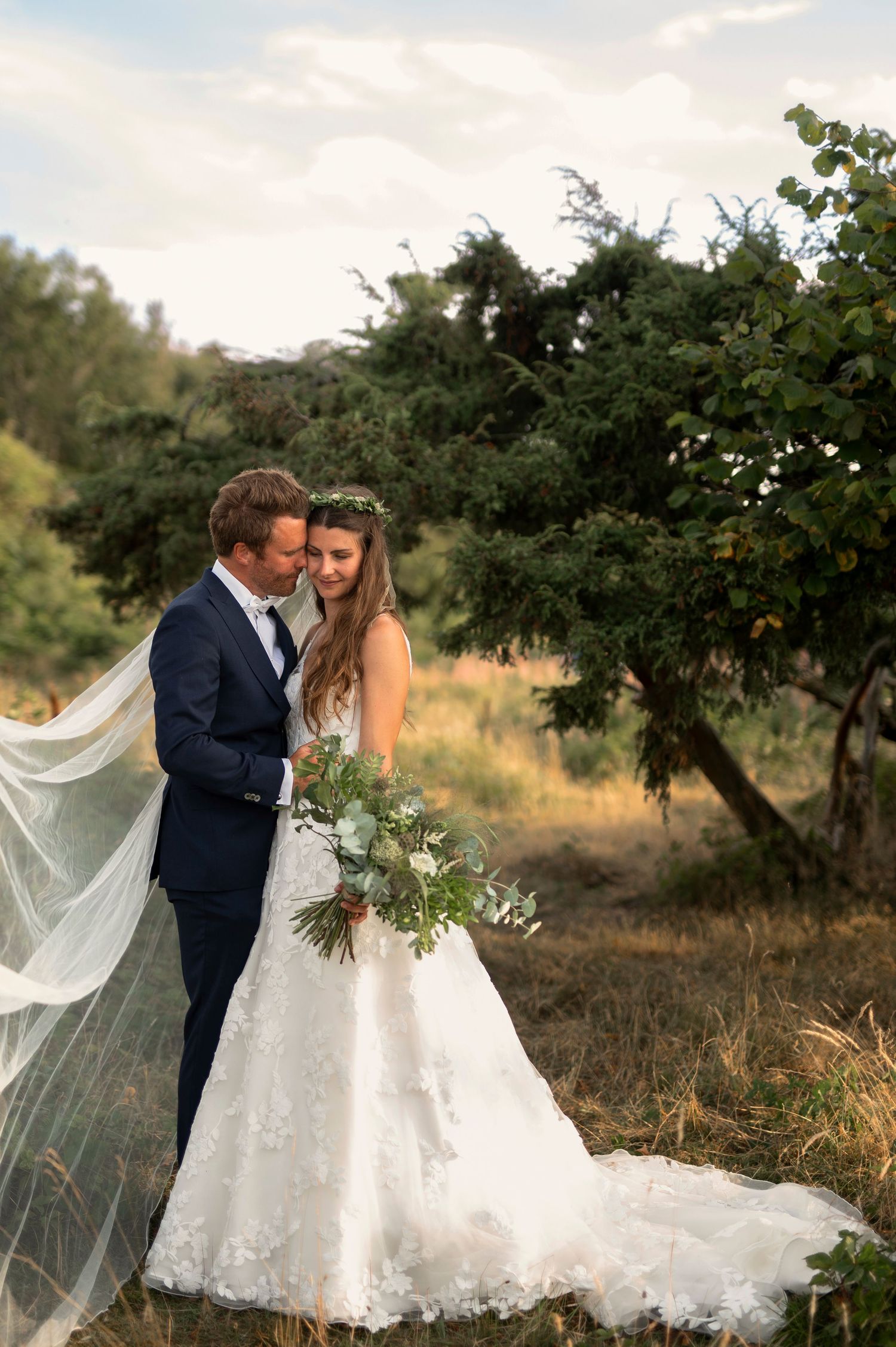 Elopement at Hovs Hallar in Skåne, Sweden with bride and groom embracing on dramatic coastal cliffs at sunset with ocean waves and moody sky