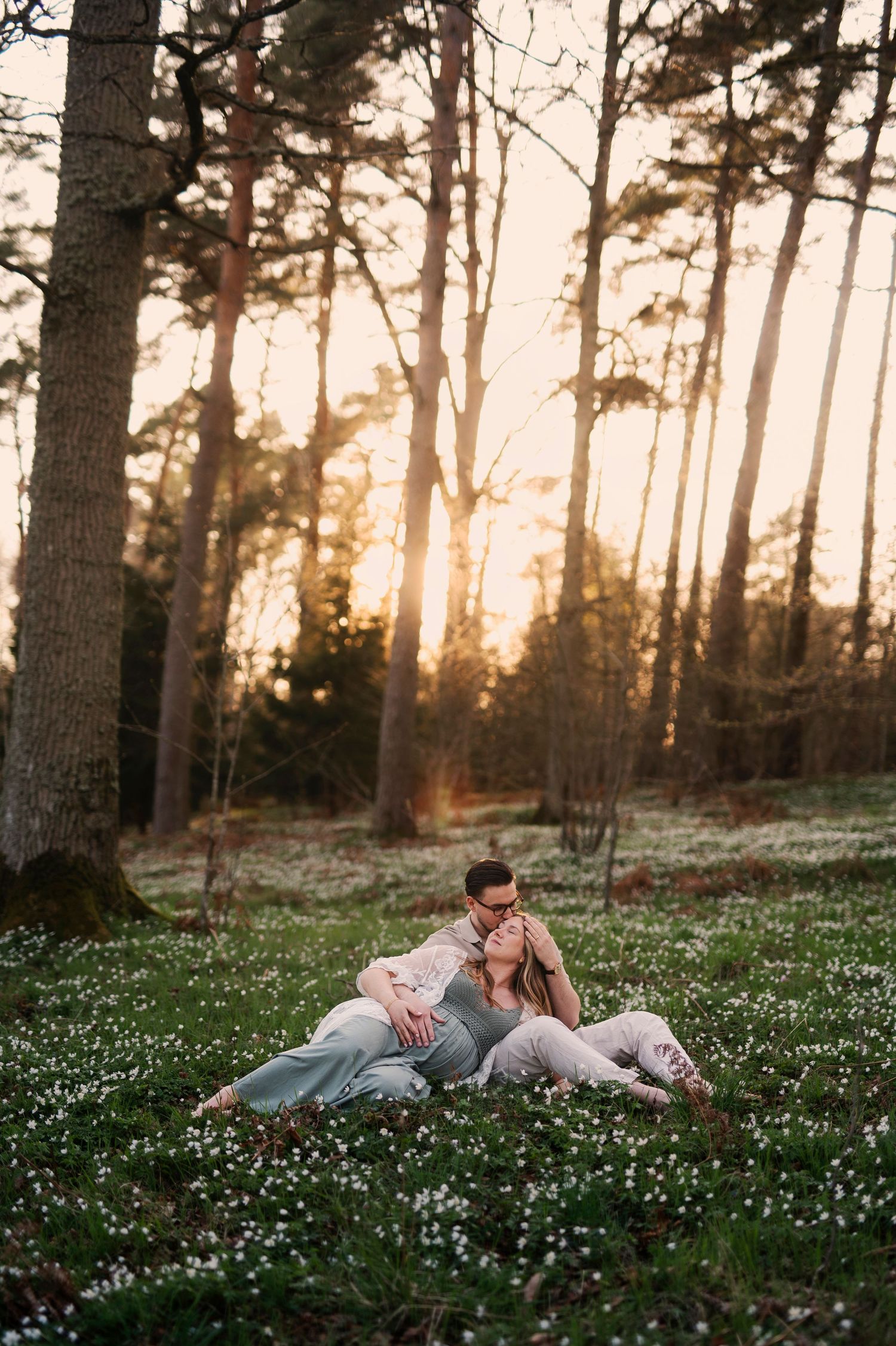 Gravidfotografering i Skåne med blivande föräldrar i skogsmiljö i gyllene kvällsljus.