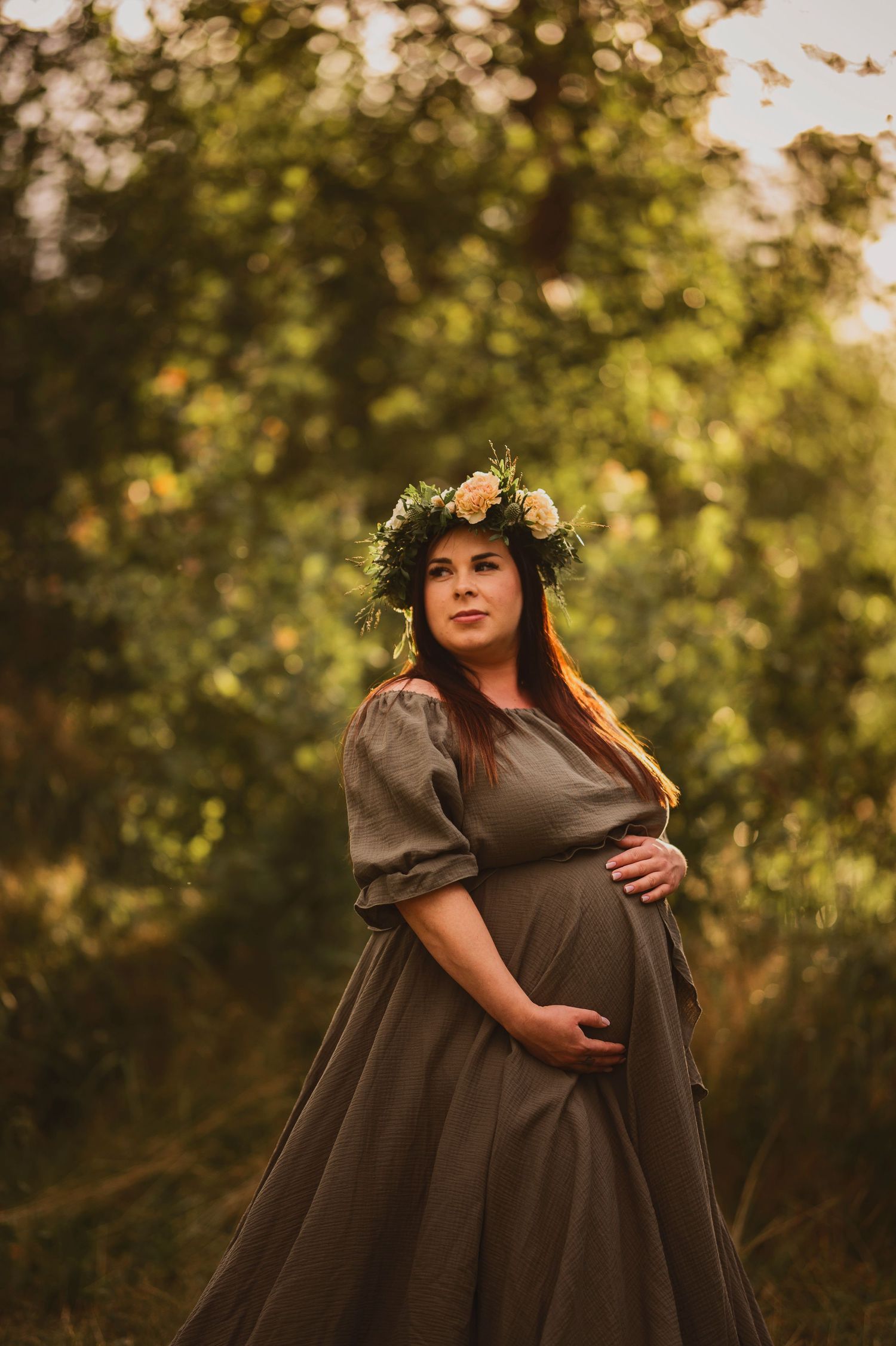 Gravidfotografering i Skåne med rustikt porträtt av blivande mamma i blomsterkrans i varmt kvällsljus.