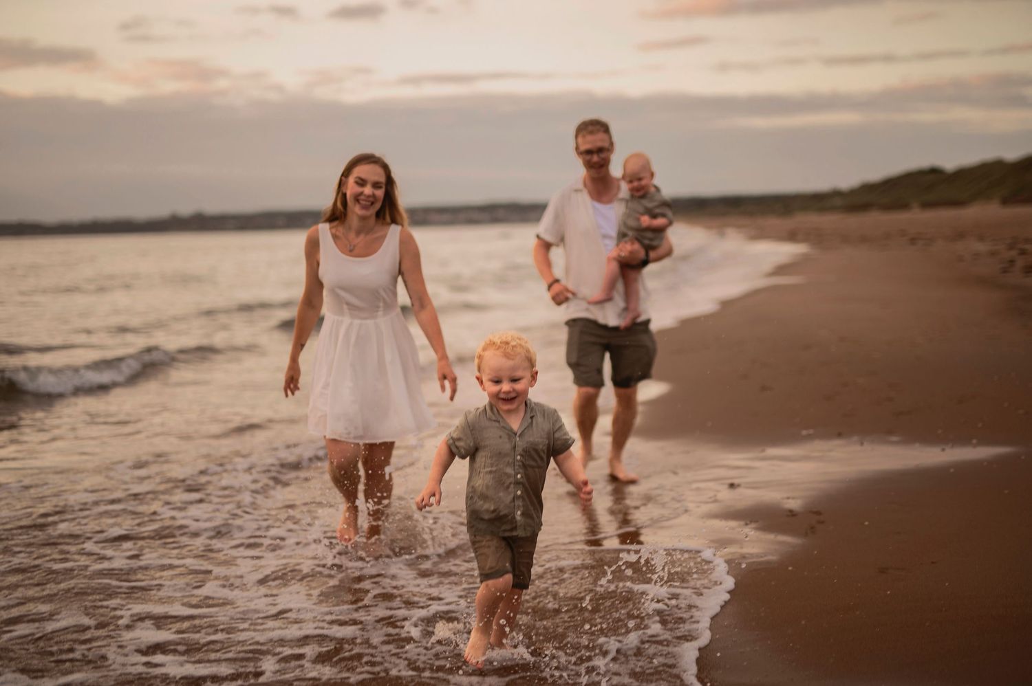 Familjefotografering i Råbocka, Ängelholm, Skåne med familj som går längs stranden i solnedgång.