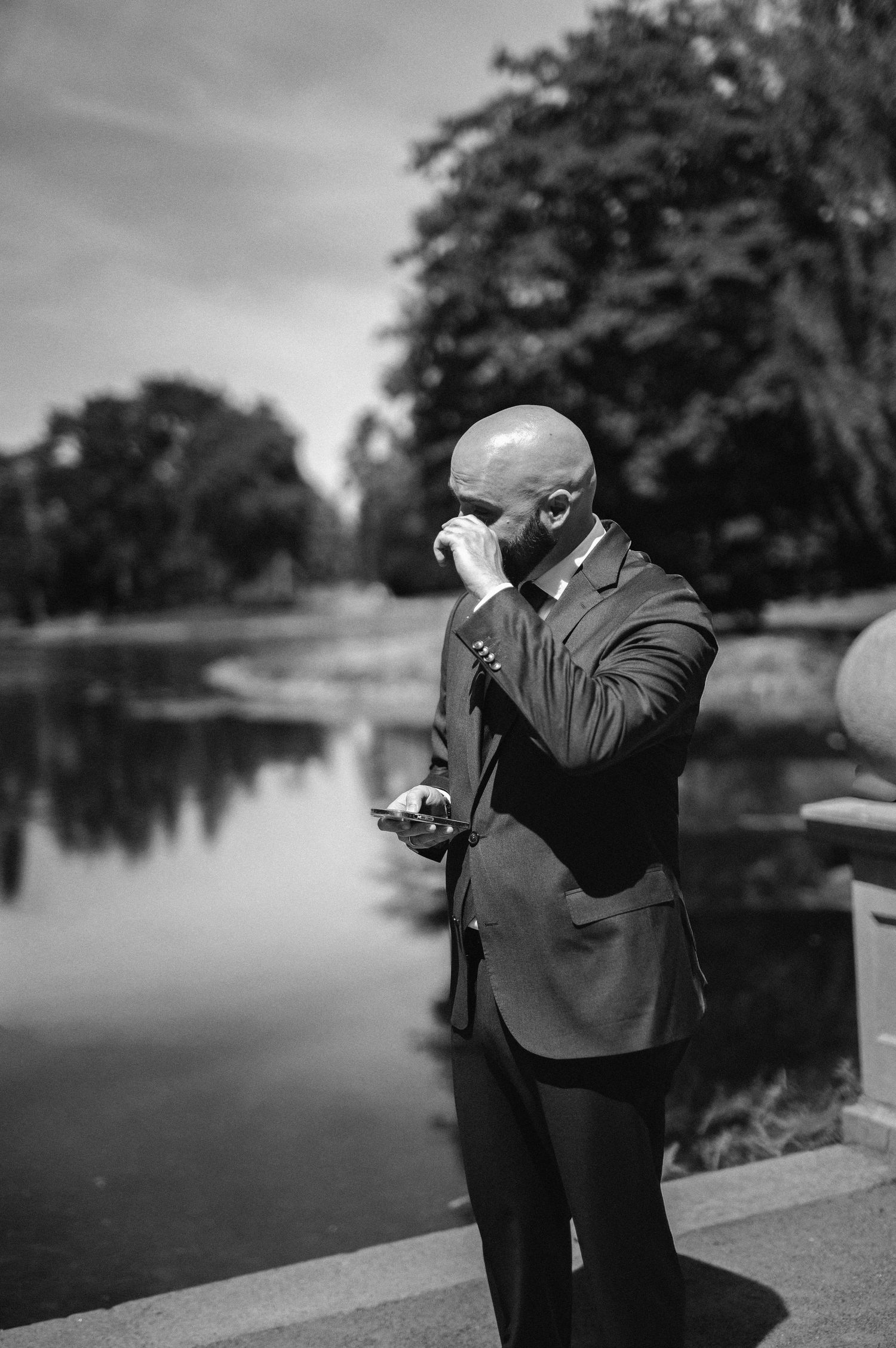 Bröllopsfotografering i Malmö med emotionell brudgum vid sjö i parkmiljö.