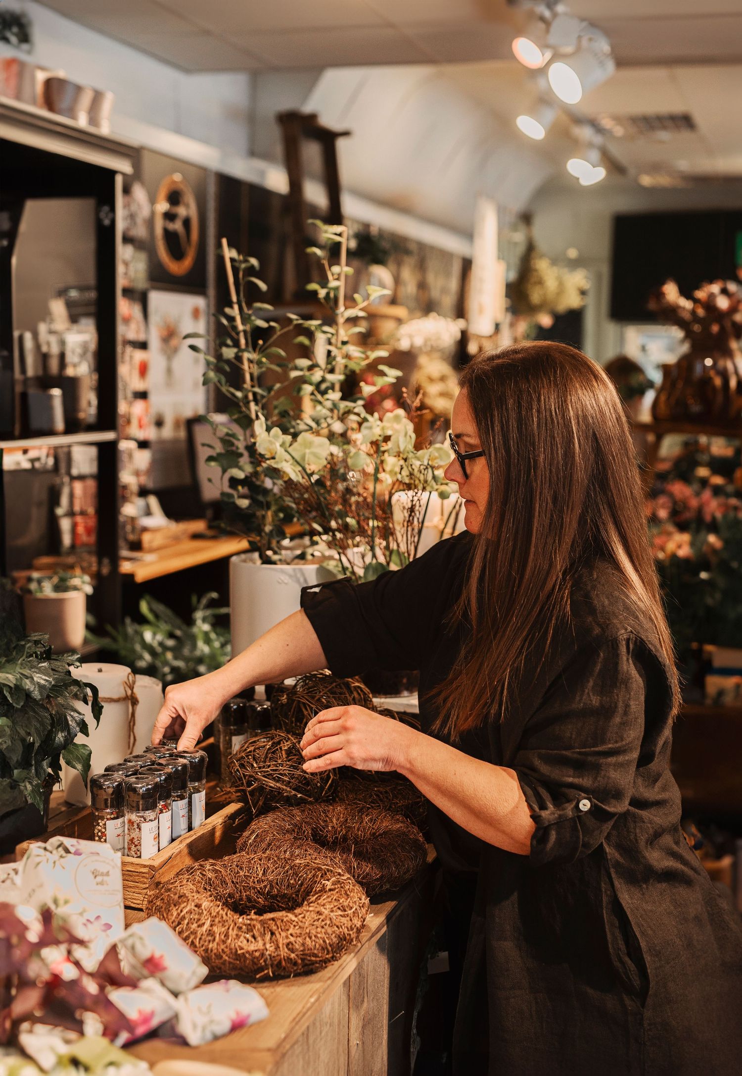 Företagsfotografering i Skåne med florist som skapar blomkrans i mysig blomsterbutik.