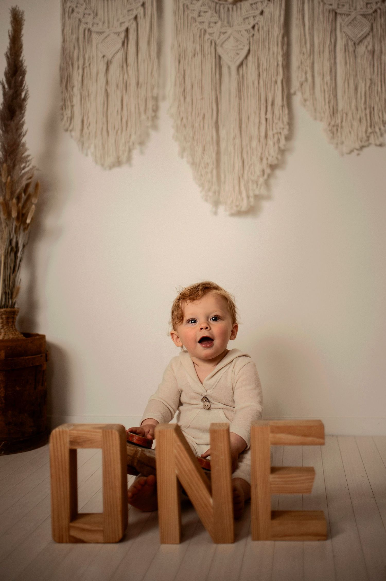 Smash the cake-fotografering i studio i Hässleholm med bebis och födelsedagstårta framför makramévägg