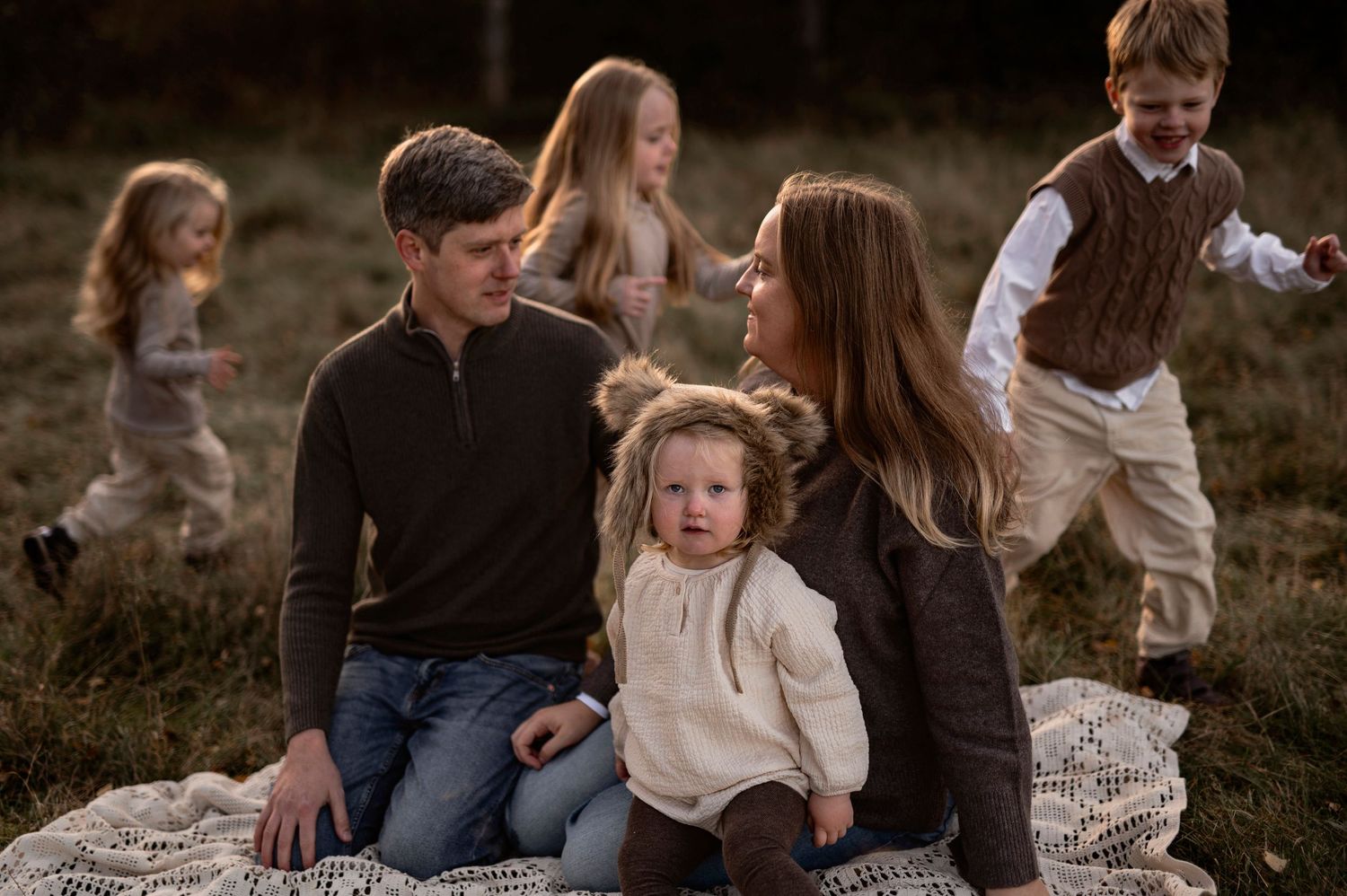 Familjefotografering i Skåne med familj på sex i dämpad natur i moody ljus på fält.