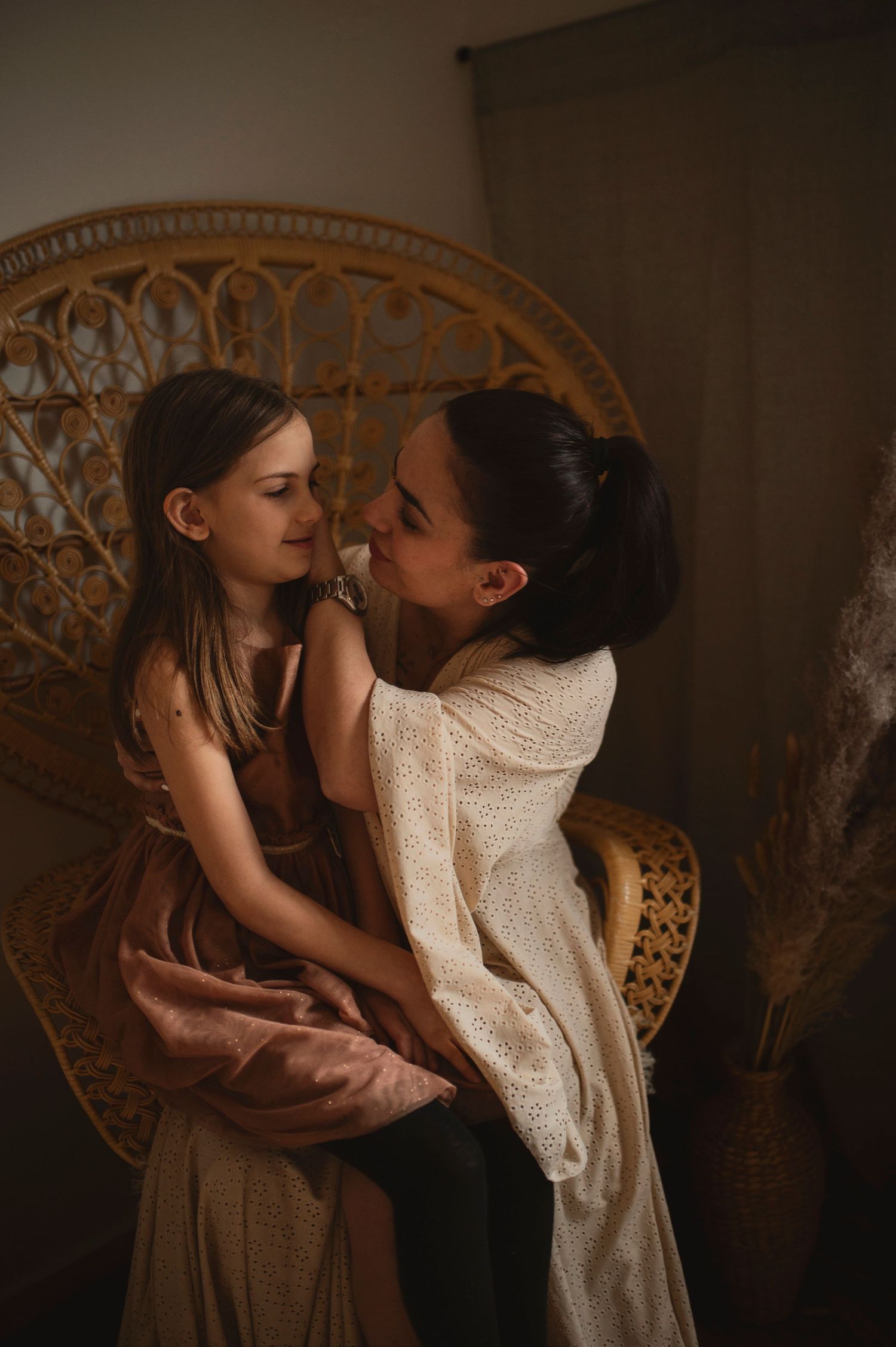 Candid moment captured against vintage rattan chair in warm atmospheric lighting.
