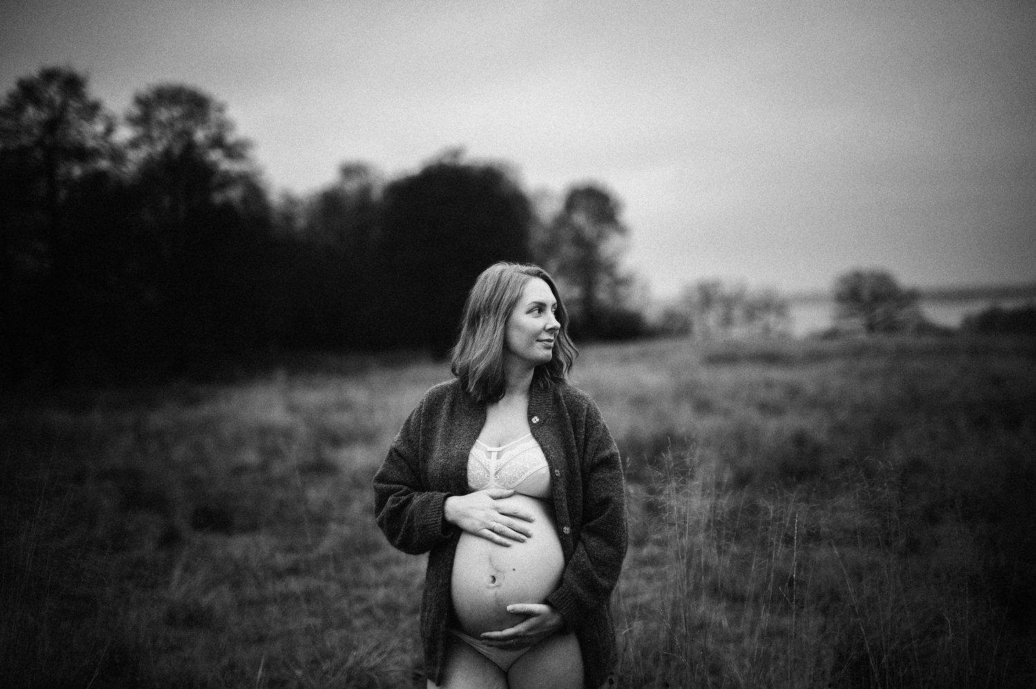 Svartvit gravidbild från en gravidfotografering i Skåne med naturligt ljus och öppna landskap.