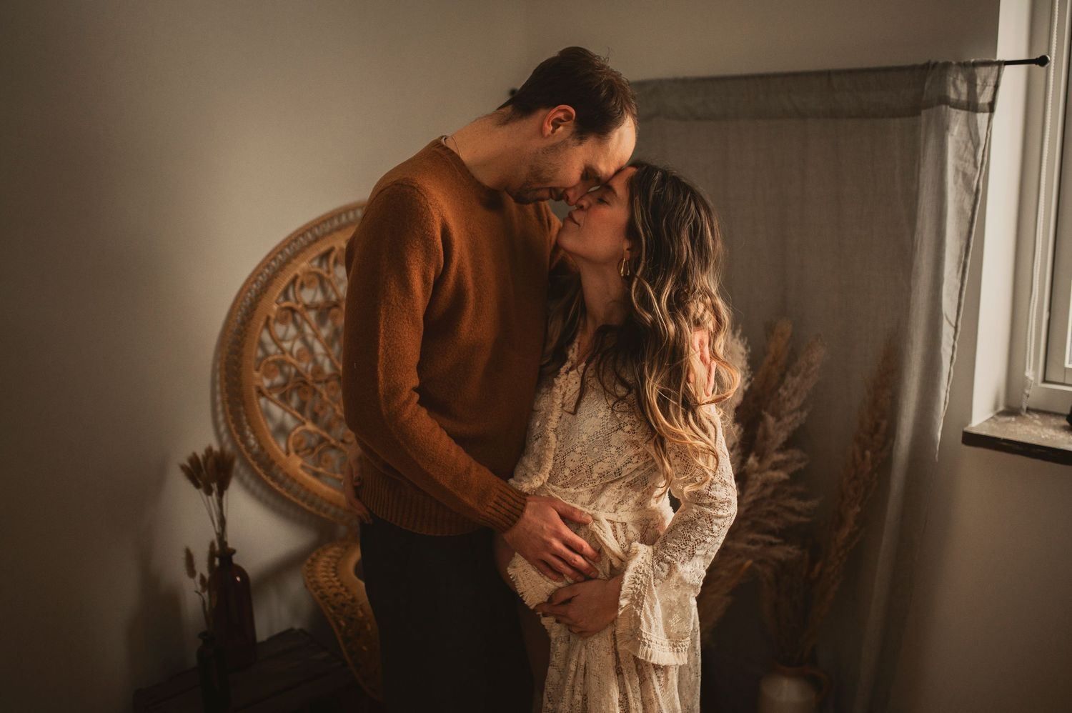 Intimate maternity photo of couple in warm tones against vintage decor.